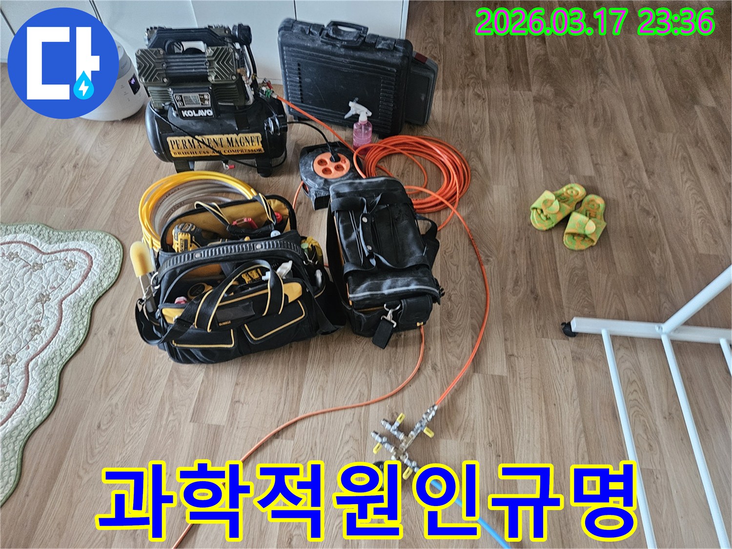 누수 탐지를 위해 준비된 전문 장비들-콤프레셔와 공압 테스트 도구-그리고 공구 가방이 바닥에 놓여 있습니다.