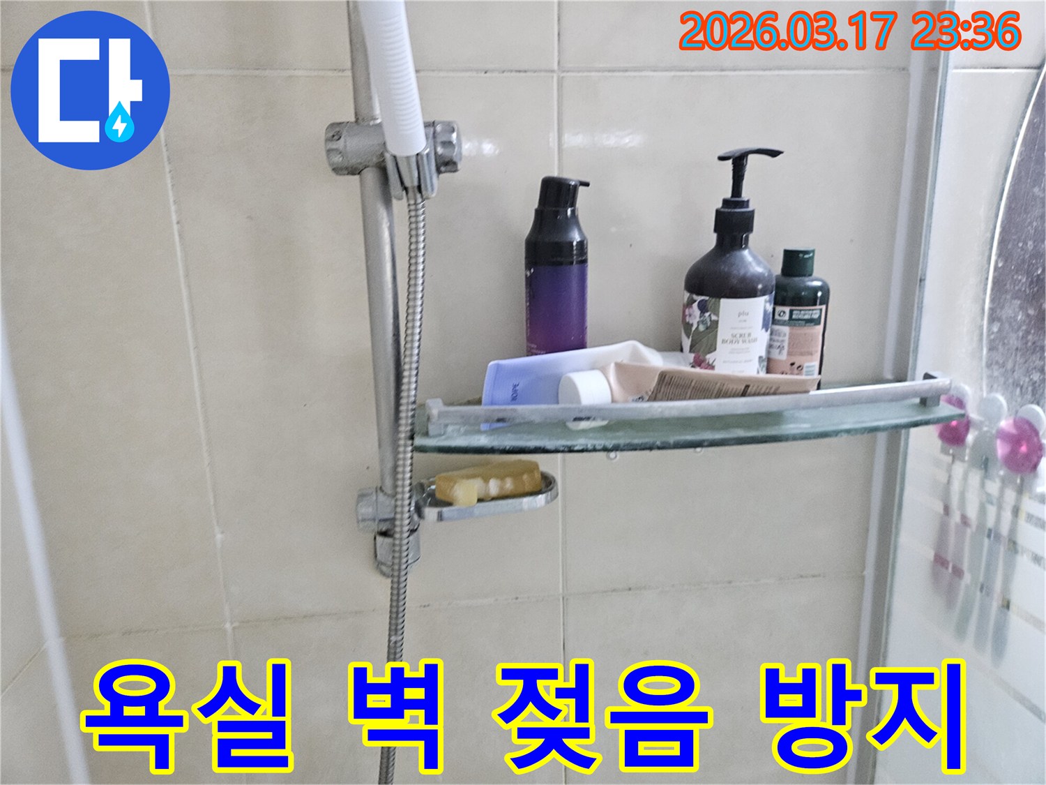 욕실 샤워기 옆-유리 선반 아래로-물방울이 맺혀있는 모습으로-벽면 젖음의 원인인 누수를 암시하는 이미지입니다