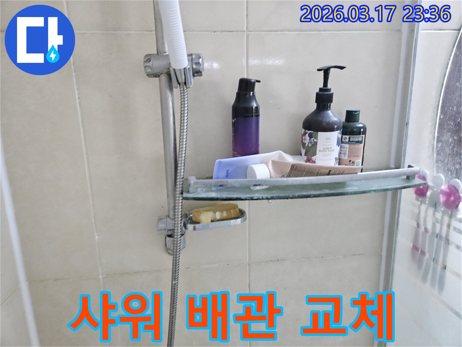 욕실 샤워기 옆-유리 선반에서-물방울이 떨어지는 모습으로-배관 교체가 필요한 누수를 암시하는 이미지입니다