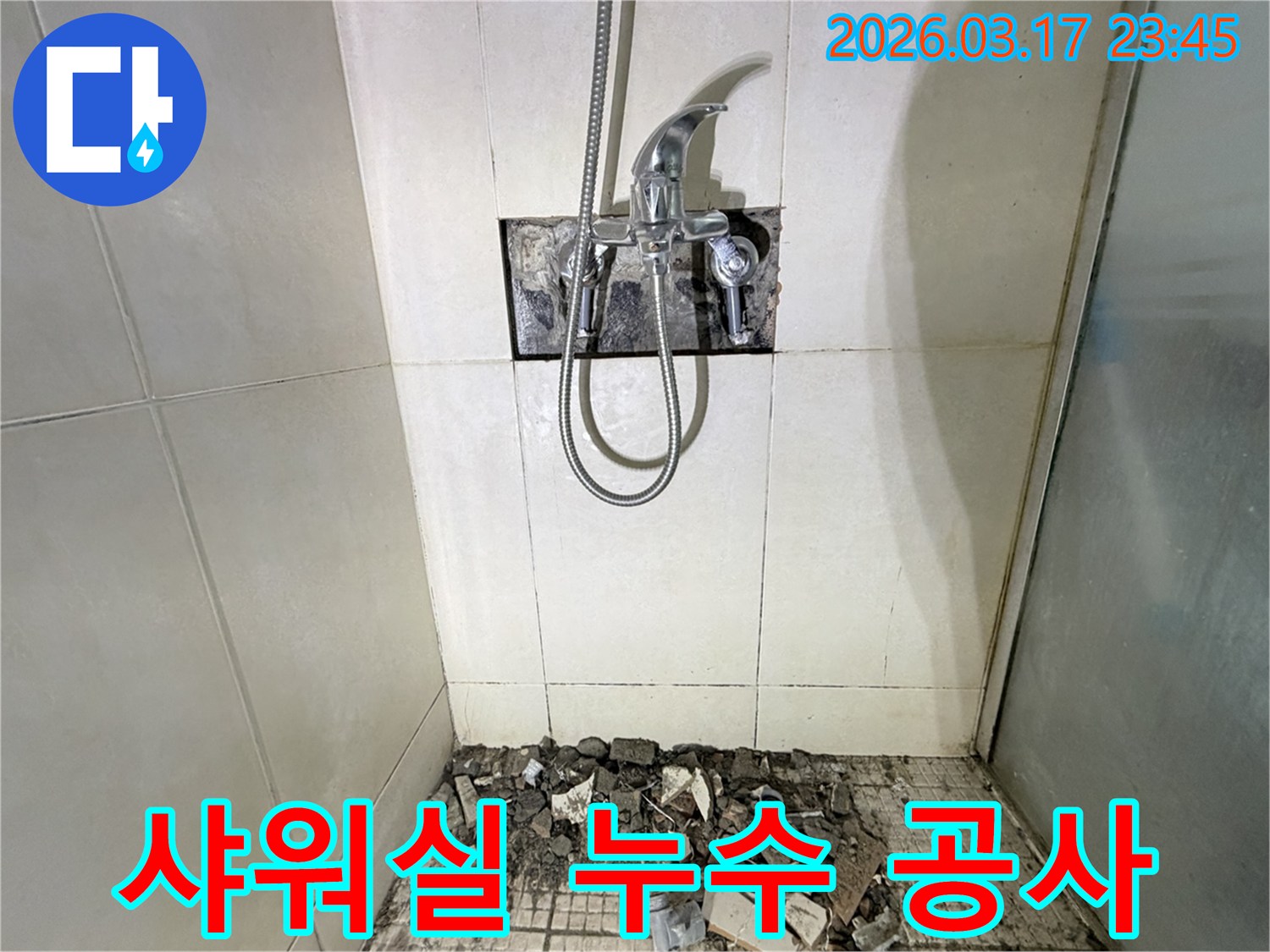 이 이미지는 욕실 샤워 공간에서 누수 공사가 진행 중인 모습을 보여줍니다-수전이 제거되고-바닥 타일이 파손된 상태입니다.