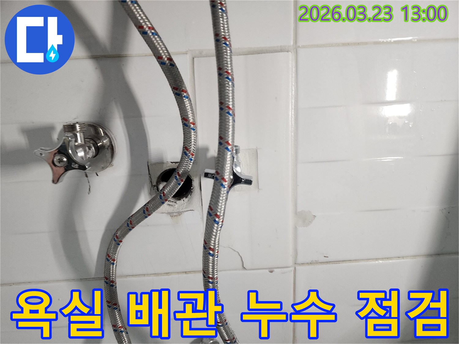 욕실 벽면에서 발생한 수도 배관 누수를 점검하는 현장 사진입니다-손상된 타일과 노출된 배관이 보입니다