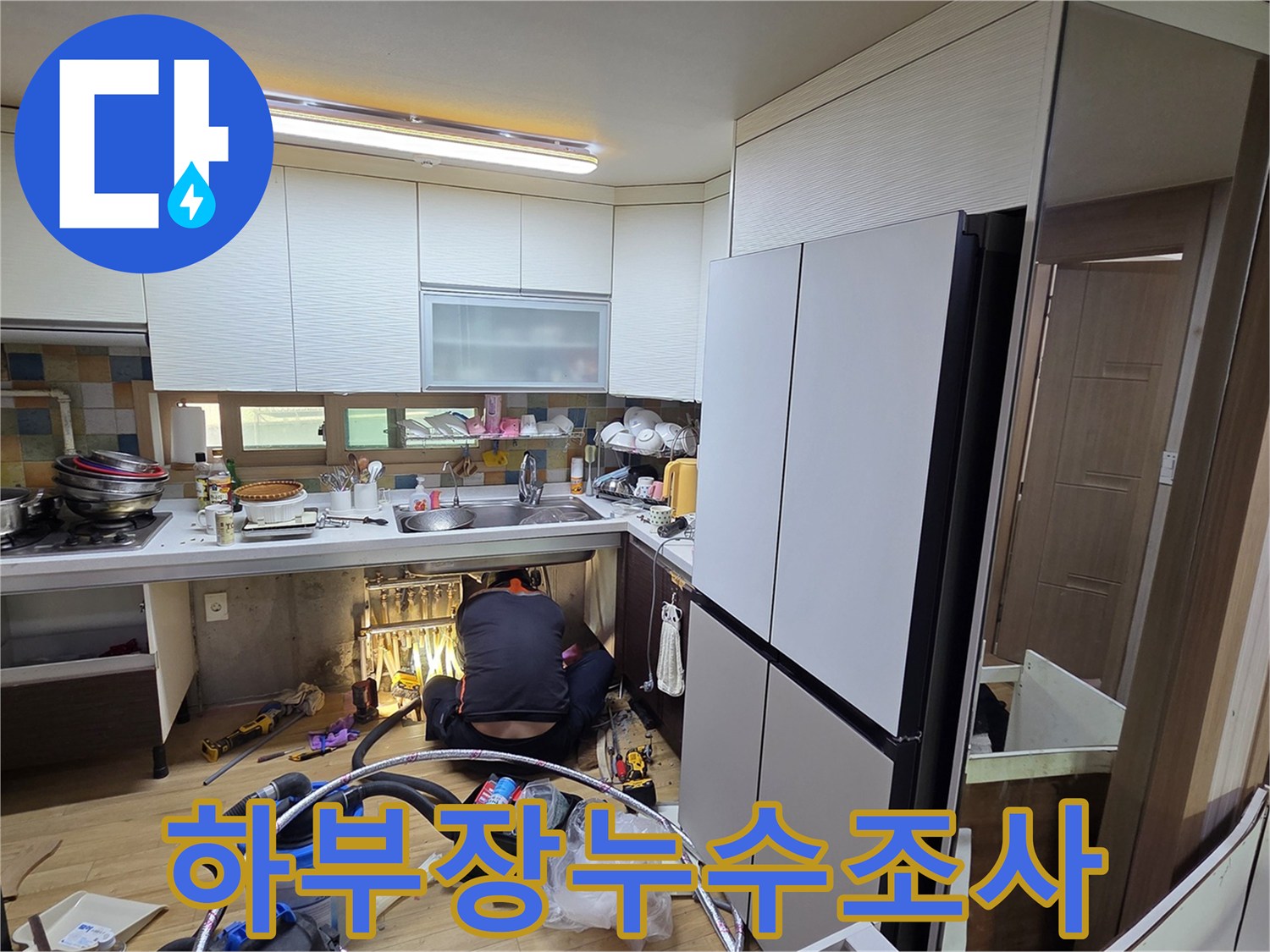 싱크대 밑 공간에서 누수 지점을 확인하는 엔지니어의 작업