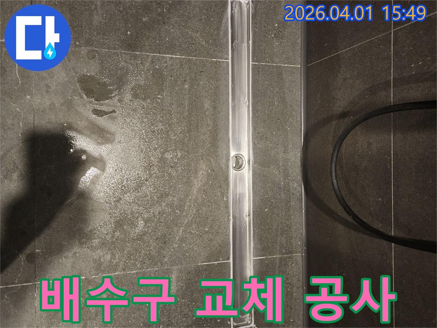어두운 타일 바닥에 설치된 직사각형 샤워 배수구-주변에 물기가 약간 남아있습니다