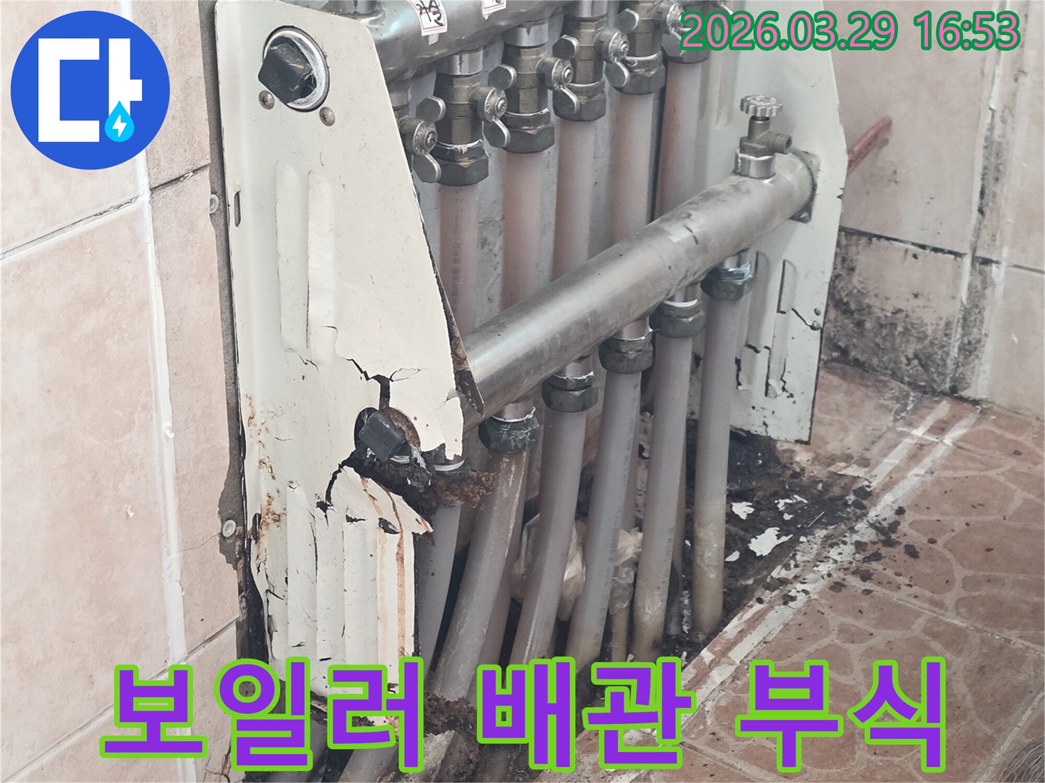 이 이미지는 낡고 부식되어 누수가 발생한 보일러 분배기 주변의 배관 상태를 상세히 보여줍니다.