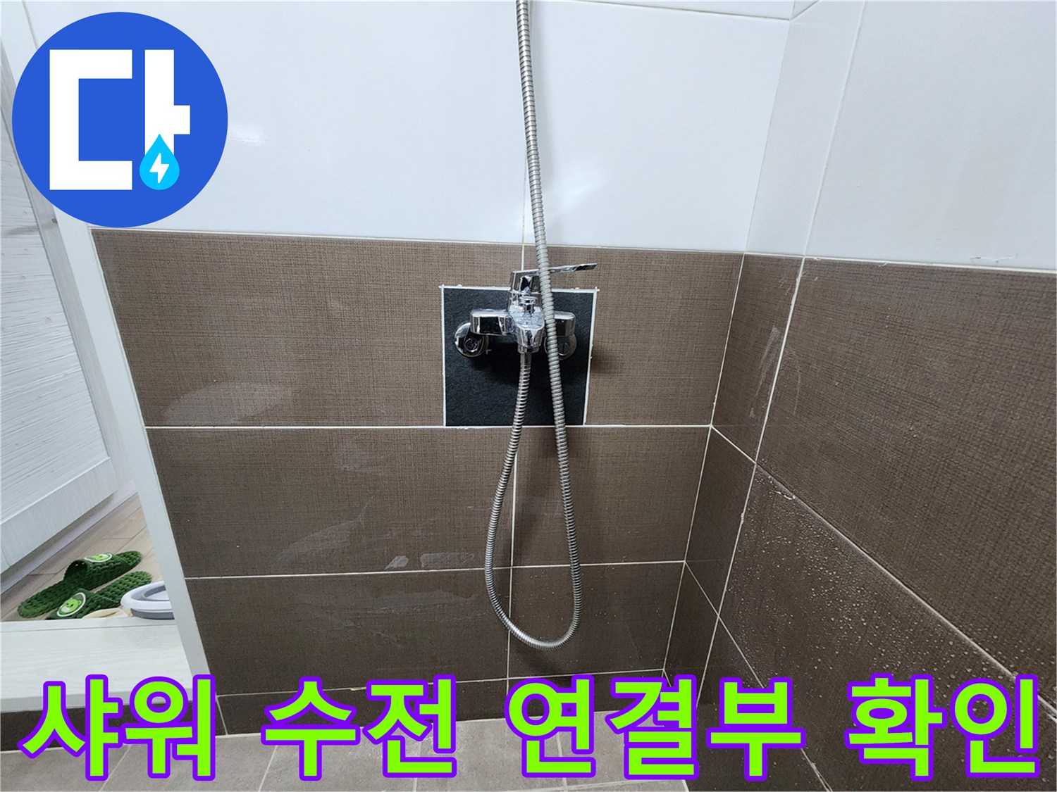 타일 벽면에 설치된 샤워기 수전의 하단부와 호스 연결 상태입니다.