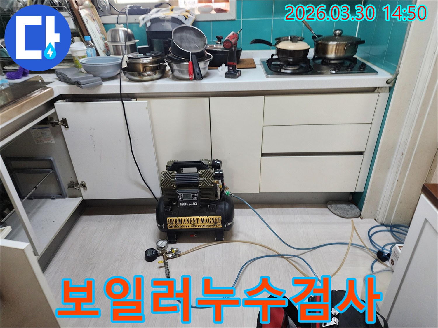 주방 하부장 근처에서-보일러 배관 누수 여부를 확인하기 위해-공압 장비가 연결되어-압력 검사를 진행하고 있습니다.