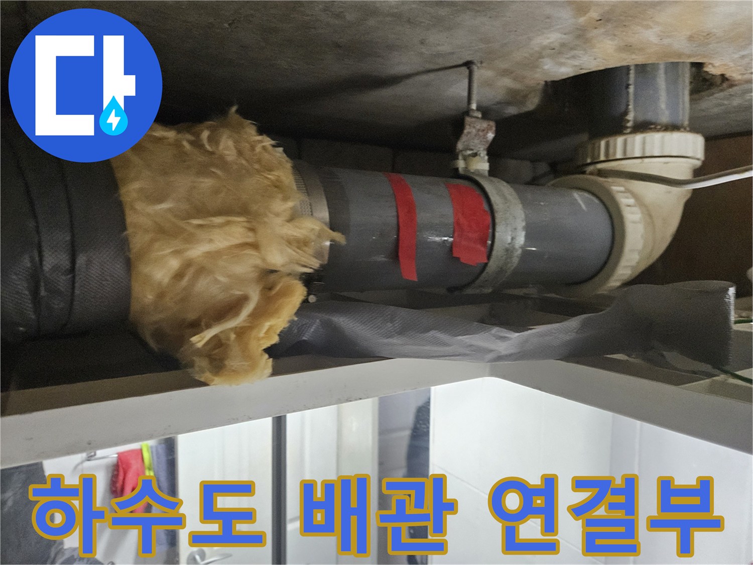 하수관 연결 부위의 붉은 테이핑과 보온재가 보이는 모습입니다.