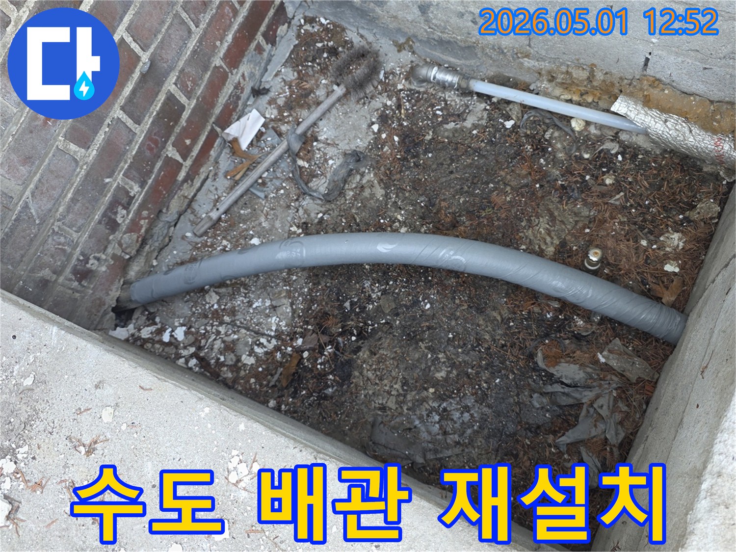 흙과 잔해 속에서-보온 처리된-회색 배관이-새롭게 연결되는-누수 수리 작업의-일부분을 담고 있습니다