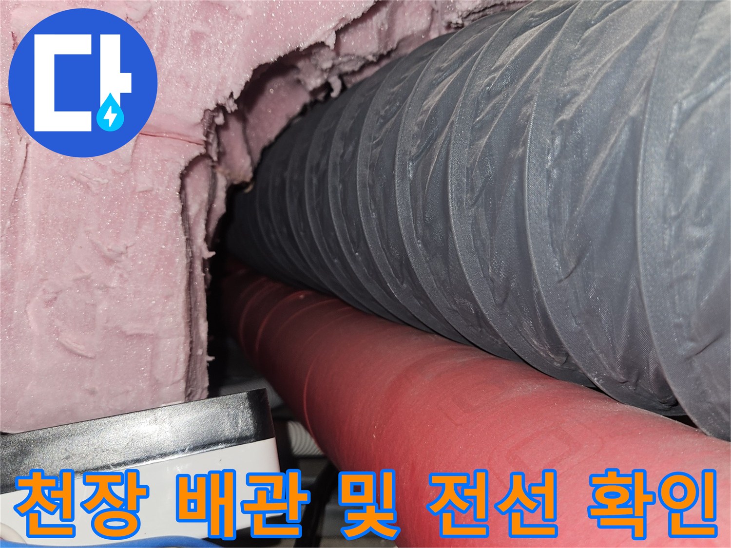 주름진 회색 관과 붉은 배관의 설비실 내부 사진