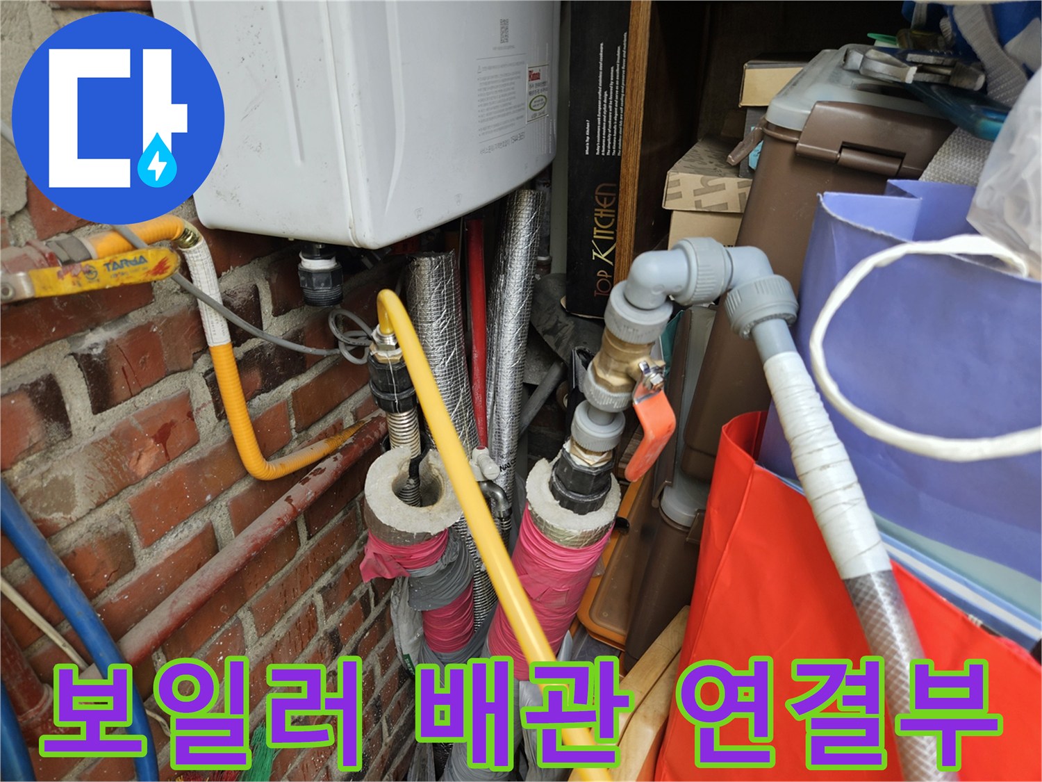 보일러 하단에 연결된 노란색 및 은색 배관의 상태를 확인하는 모습