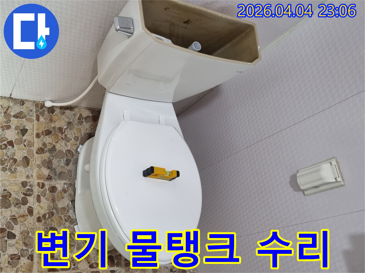 변기 물탱크가 열려 내부 부품이 노출된 상태로-수평계가 변기 시트 위에 놓여-물탱크 수리 준비가 완료되었습니다