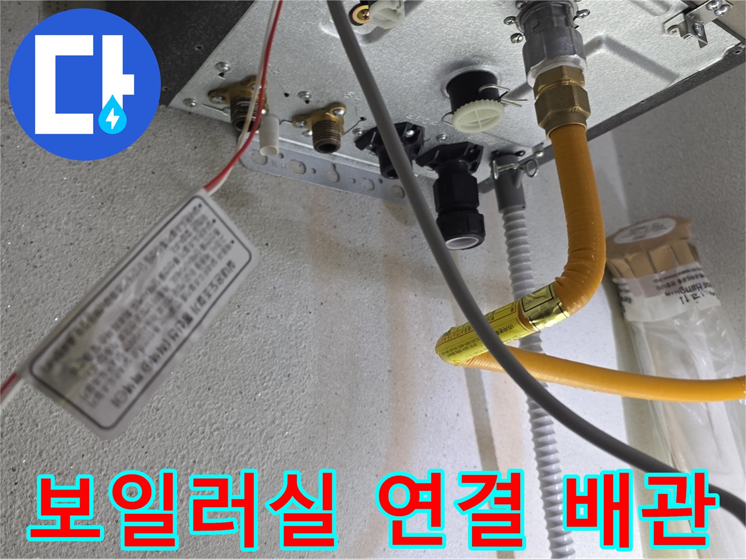 노란색 배관과 금속 부품이 연결된 보일러 하단부의 모습