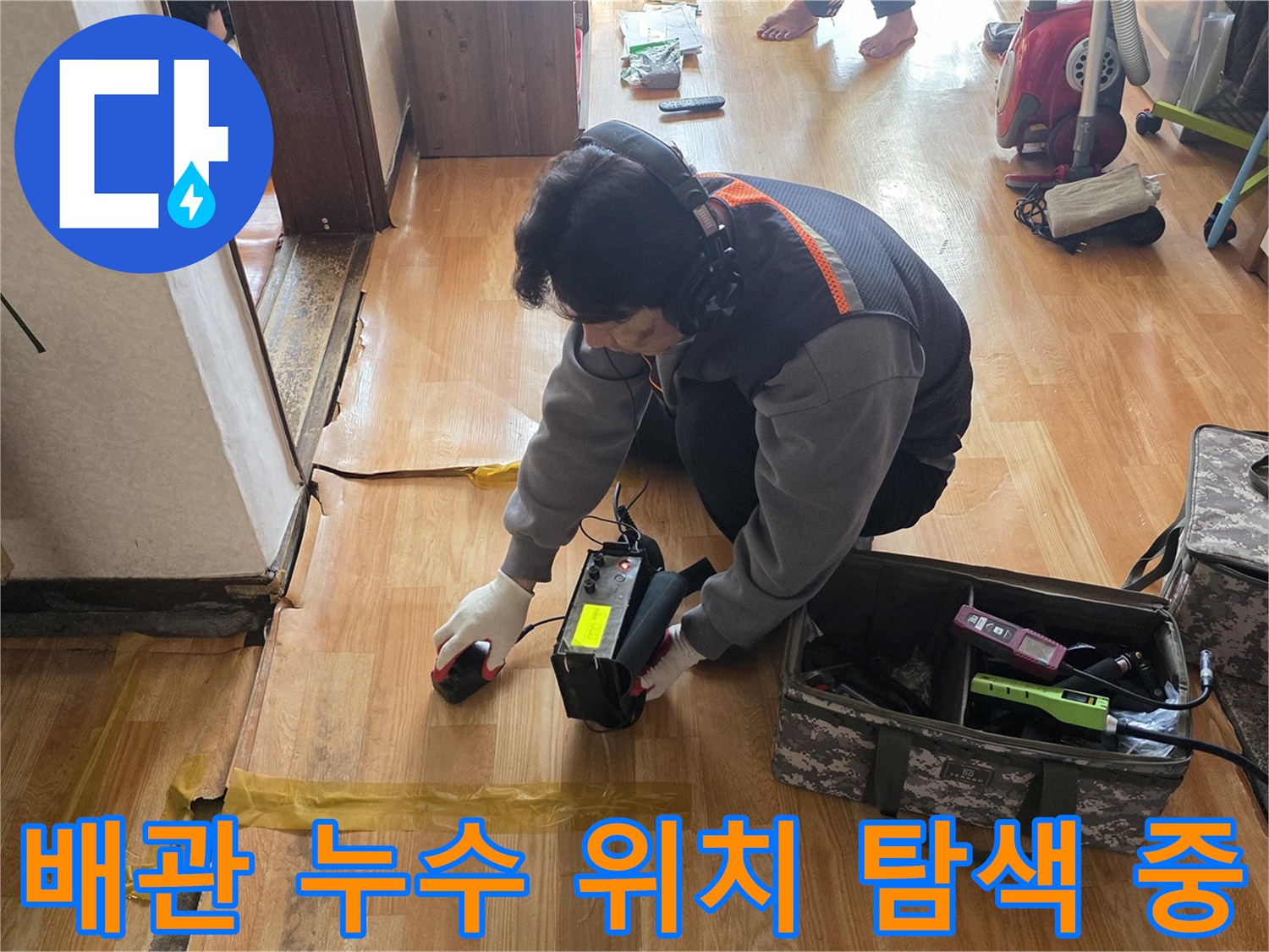 바닥재 근처에서 가스 누출을 감지하기 위해 정밀 탐지기를 조작하는 엔지니어의 모습입니다.