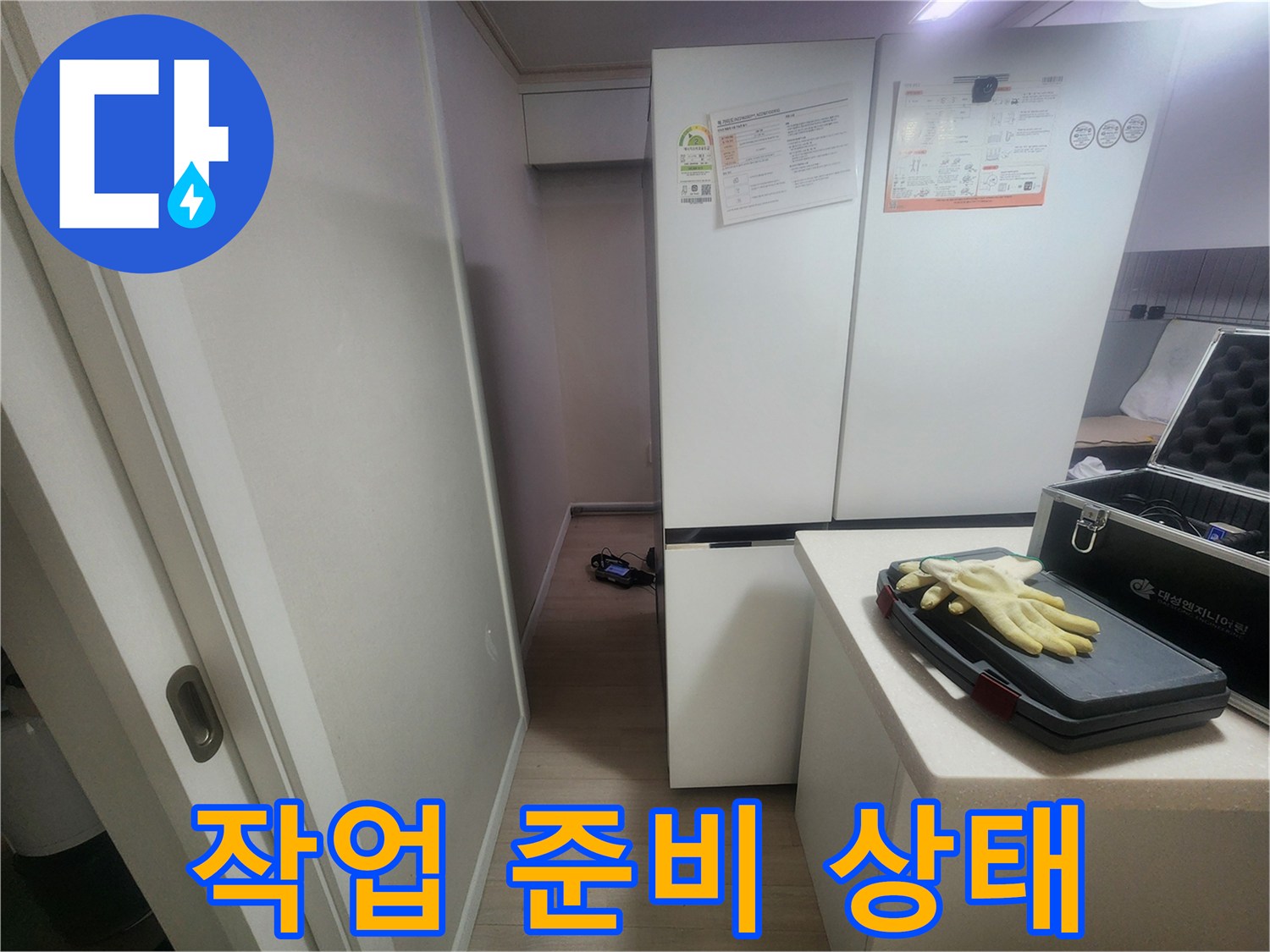 냉장고 옆 테이블 위에 놓인 일회용 장갑과 탐지기 케이스