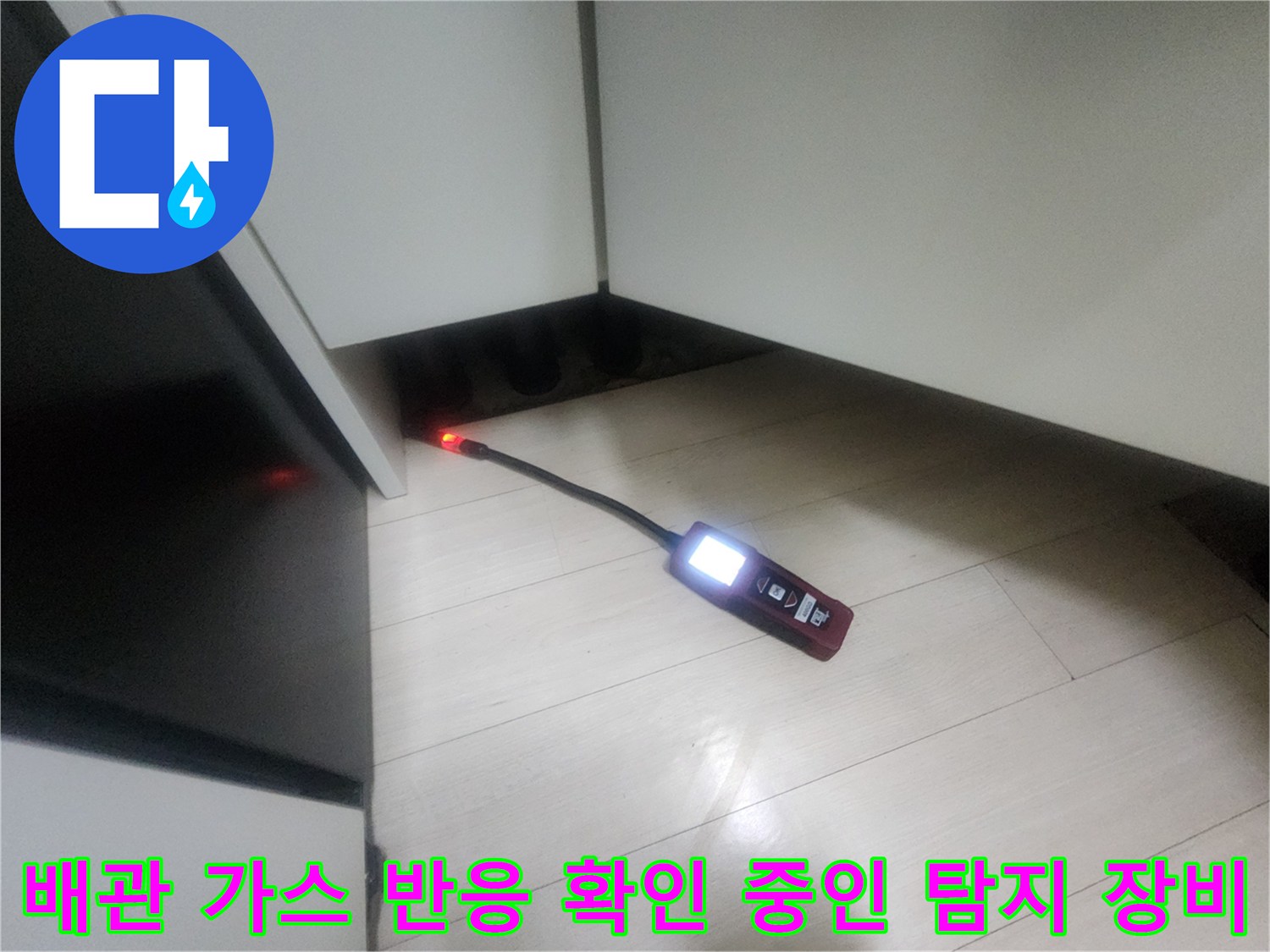 어두운 하부장 밑 공간에서-작동 중인 휴대용 가스 탐지기