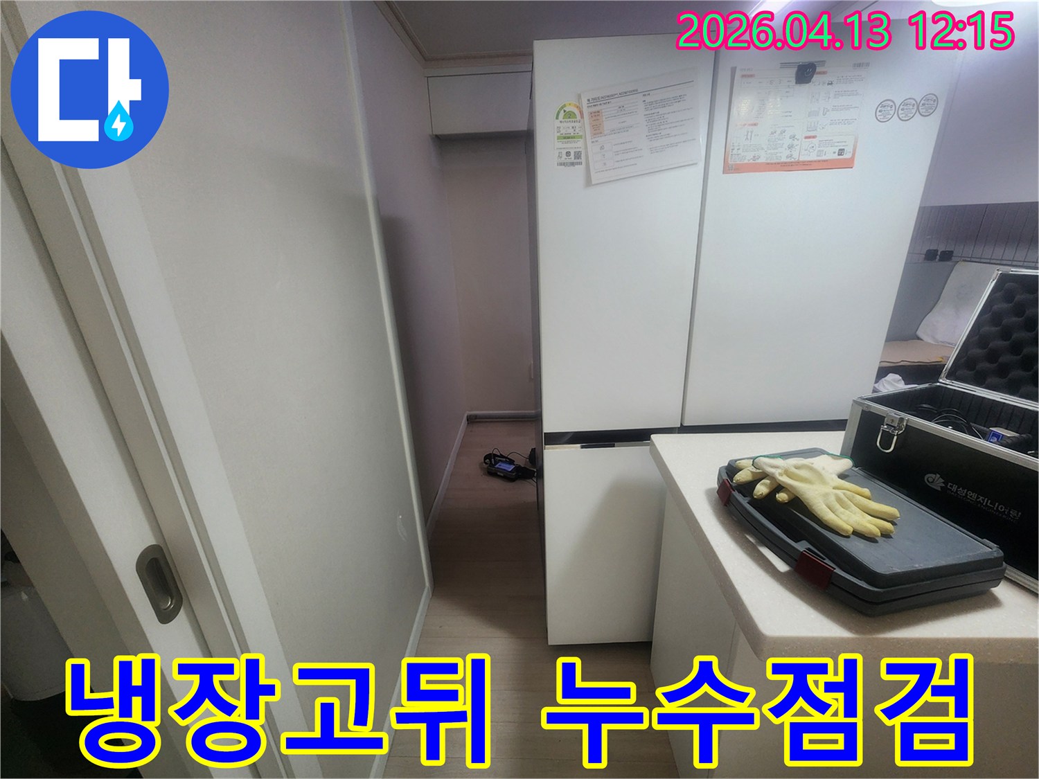 작업용 장갑과 공구함이 놓인 주방 카운터와-그 옆에 냉장고가 보이는 누수 탐지 현장