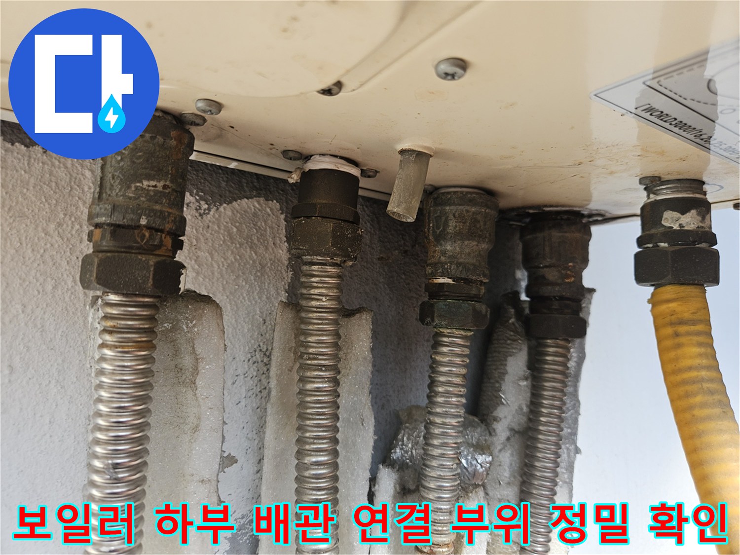 금속 주름관과 노란색 호스가 보일러 본체에 연결된 모습
