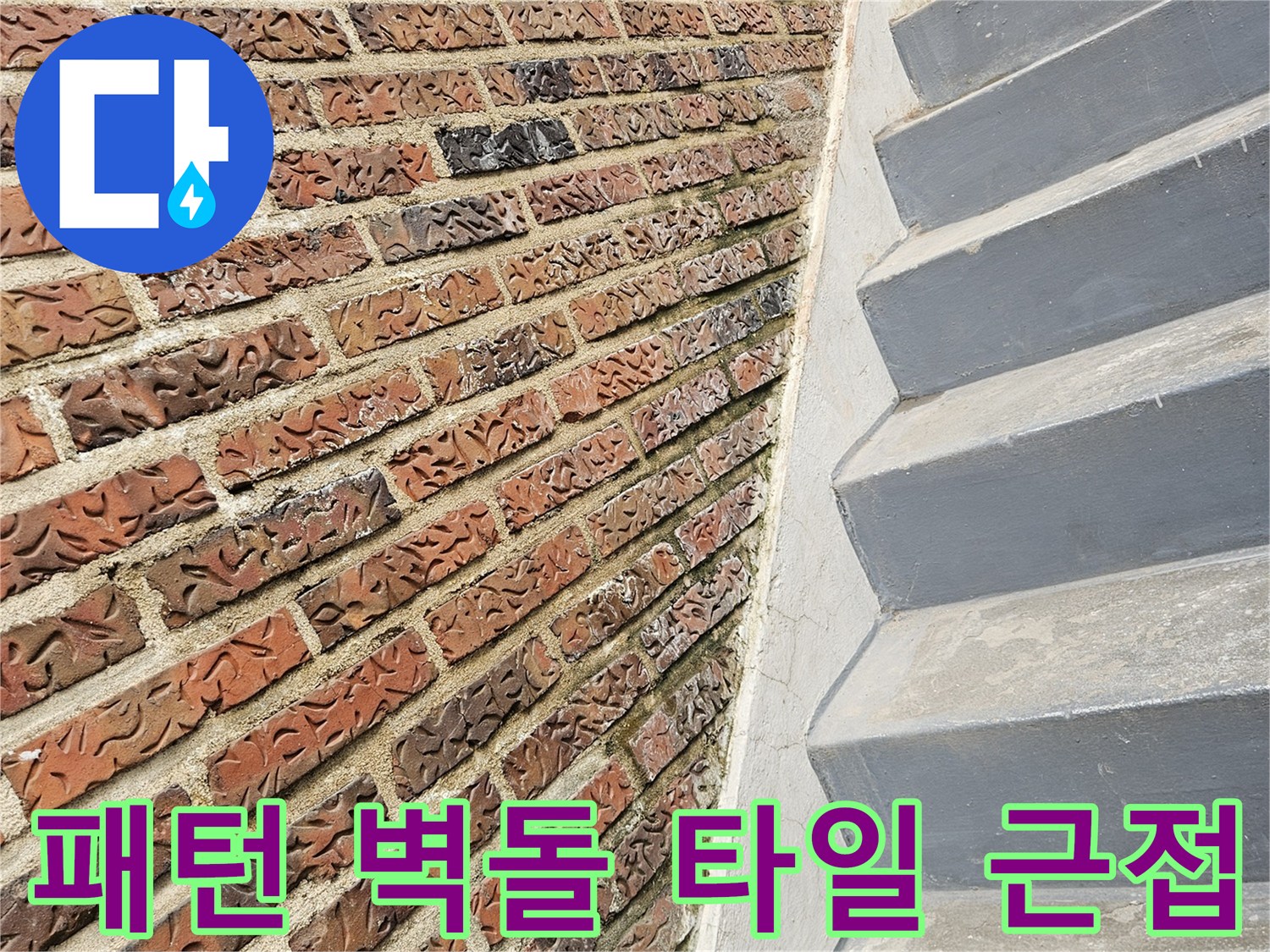 복잡한 문양의 붉은색 계열 타일과 회색 벽면 구조물 하단의 모습입니다.