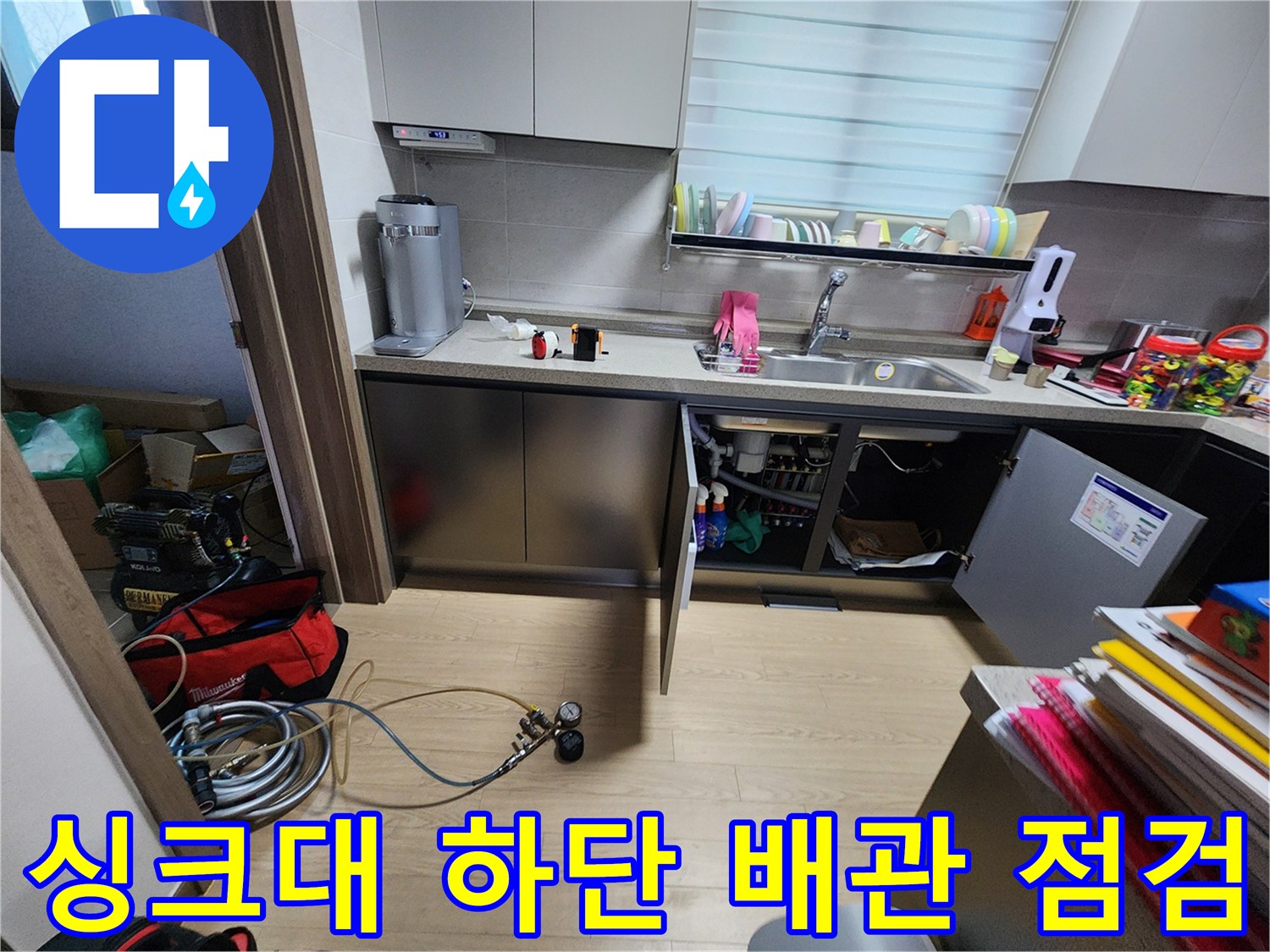 주방 싱크대 하부장 내부의 복잡한 배관과 가스 탐지 장비 모습