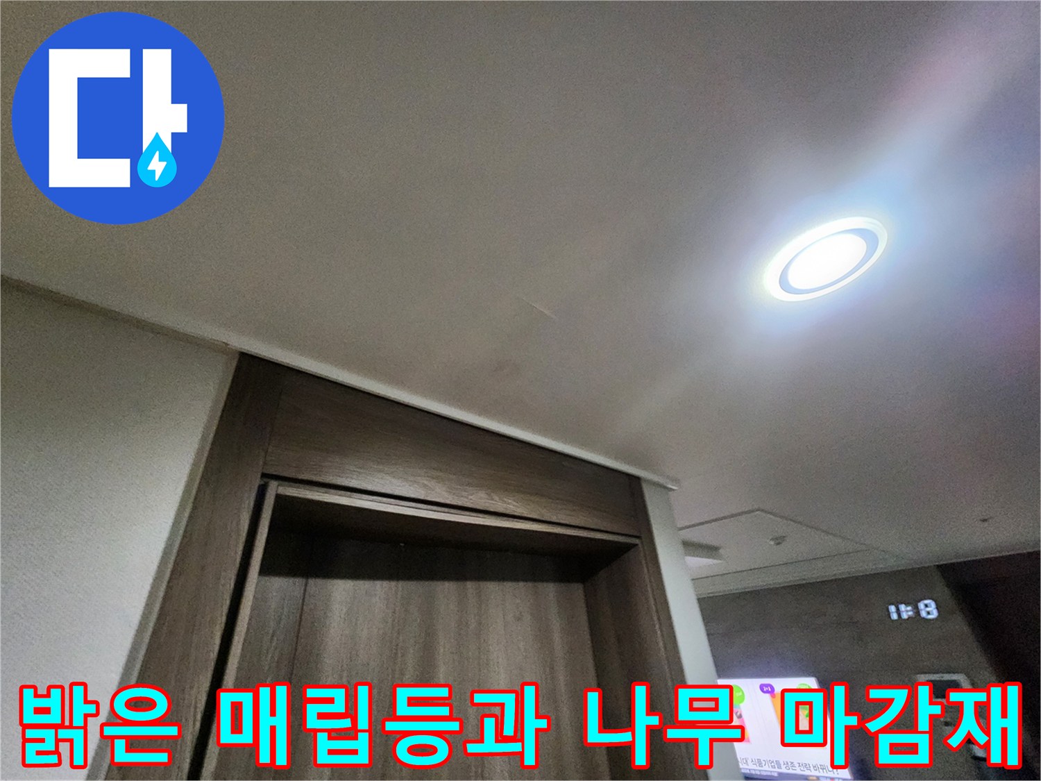 천장의 밝은 조명 빛이 비치는 벽면의 목재 마감 부위입니다.