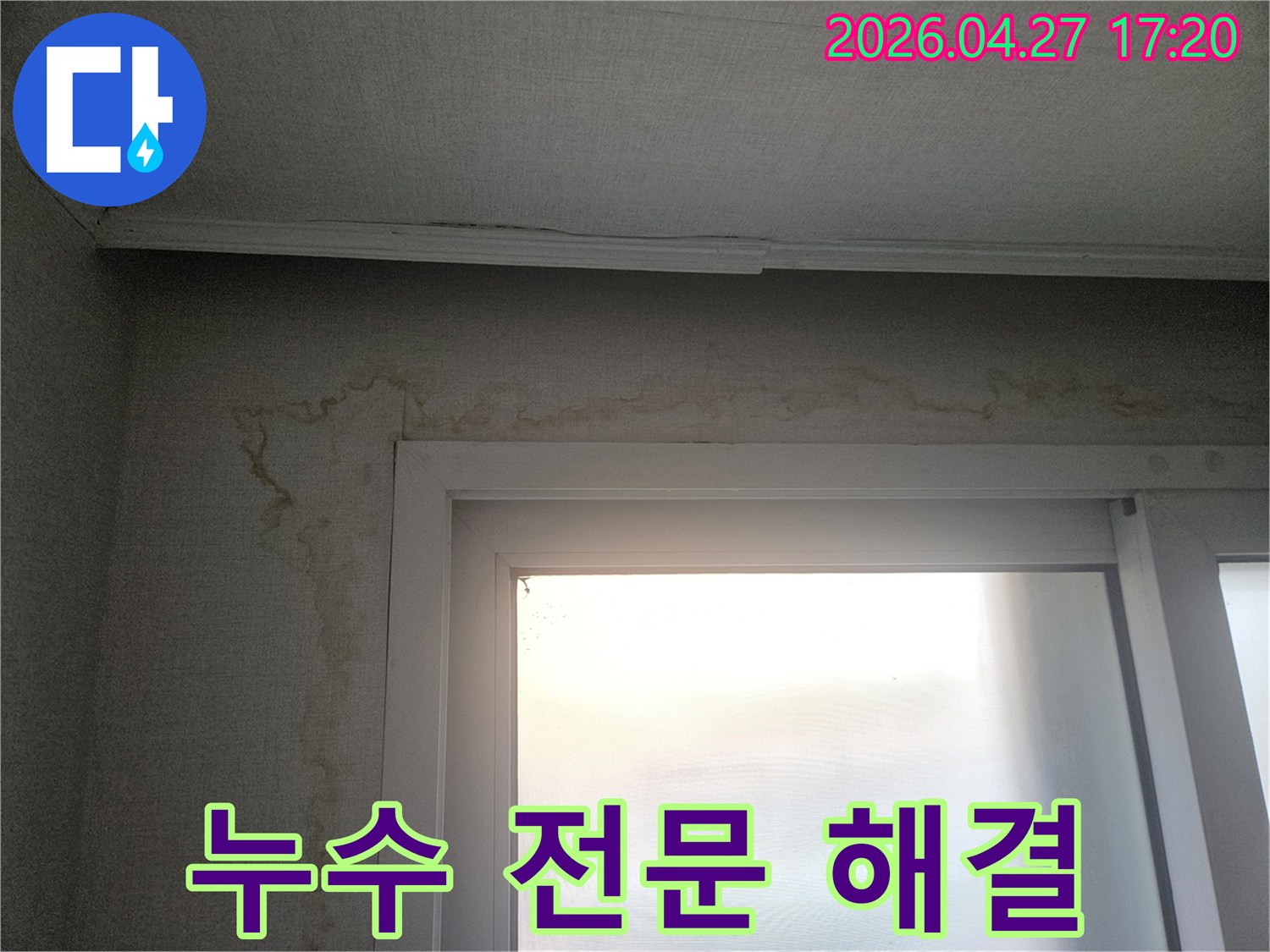 창문 옆 벽면에-누수로 인해 발생한-누런 물자국과-벽지 손상이 보이는-실내 누수 현장입니다.