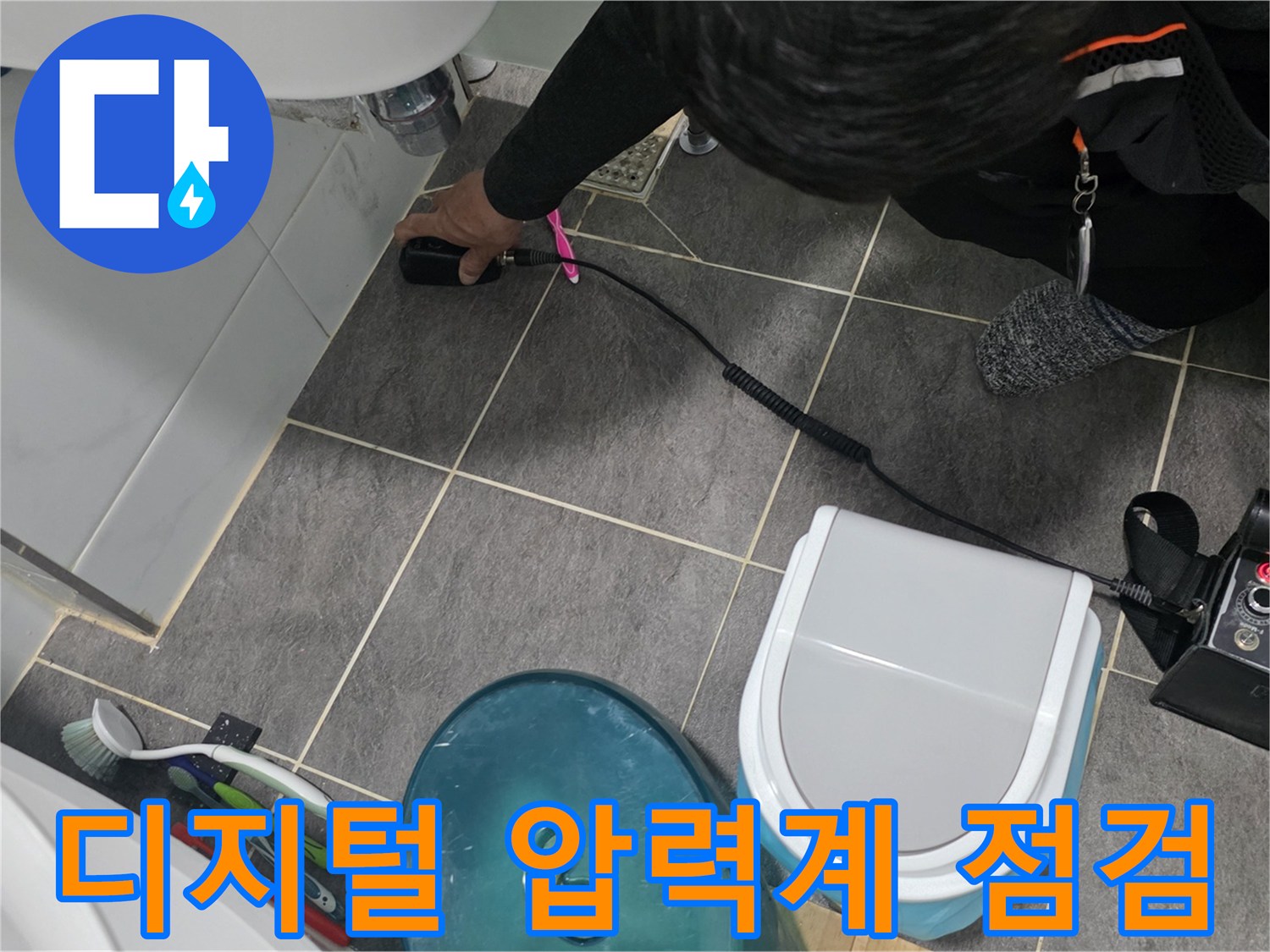 욕실 바닥 배관의 누수 여부를 확인하기 위해 디지털 압력 게이지를 연결하여 공압 검사를 진행하는 모습입니다.