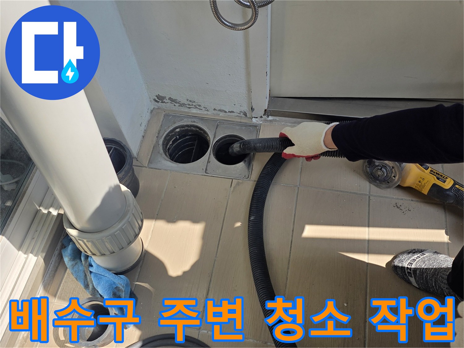 화장실 배수구 주변의 이물질을 진공청소기로 제거하는 모습