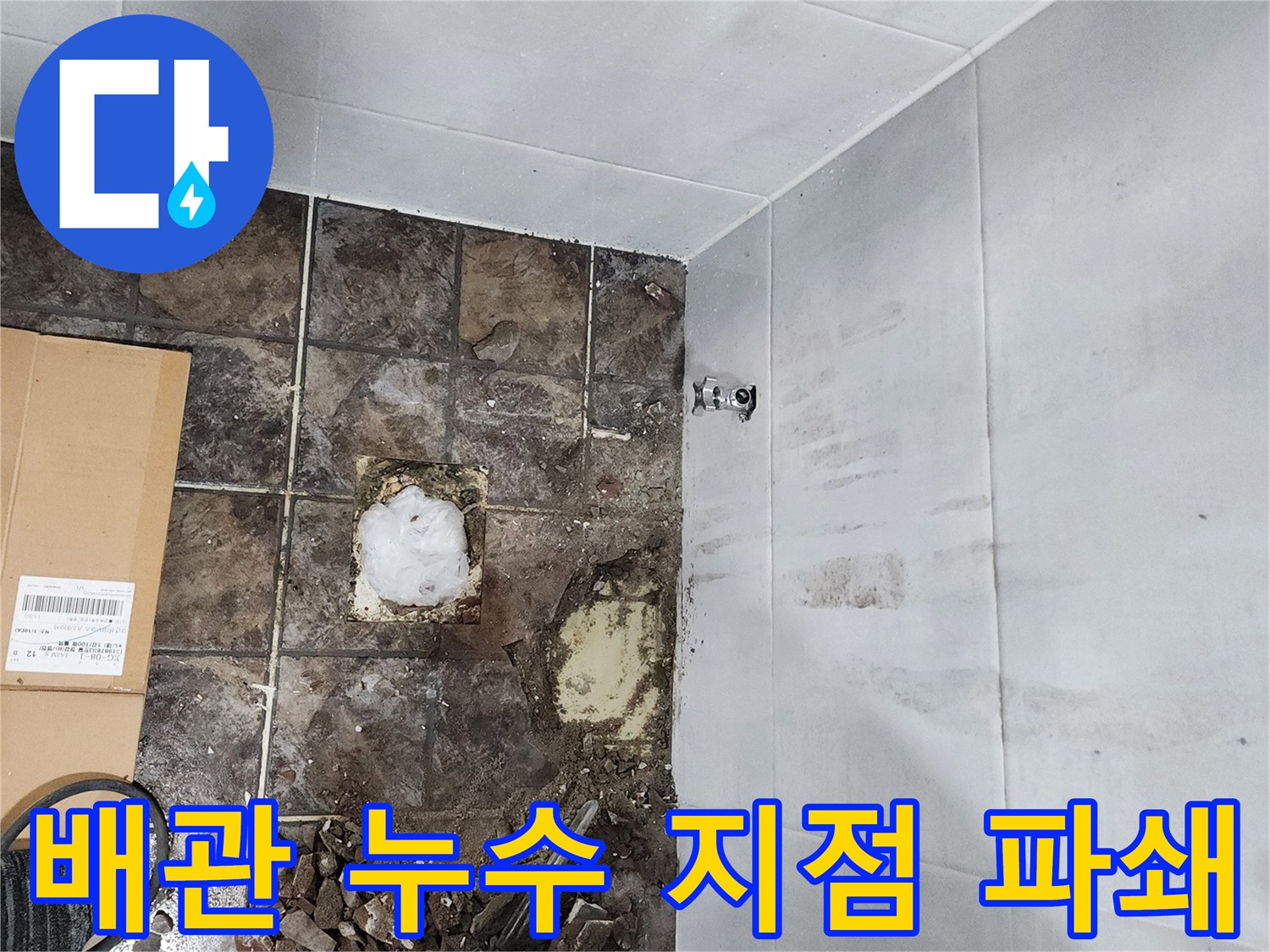 욕실 바닥 타일을 제거하여 노출된 배관 연결 부위 점검 중