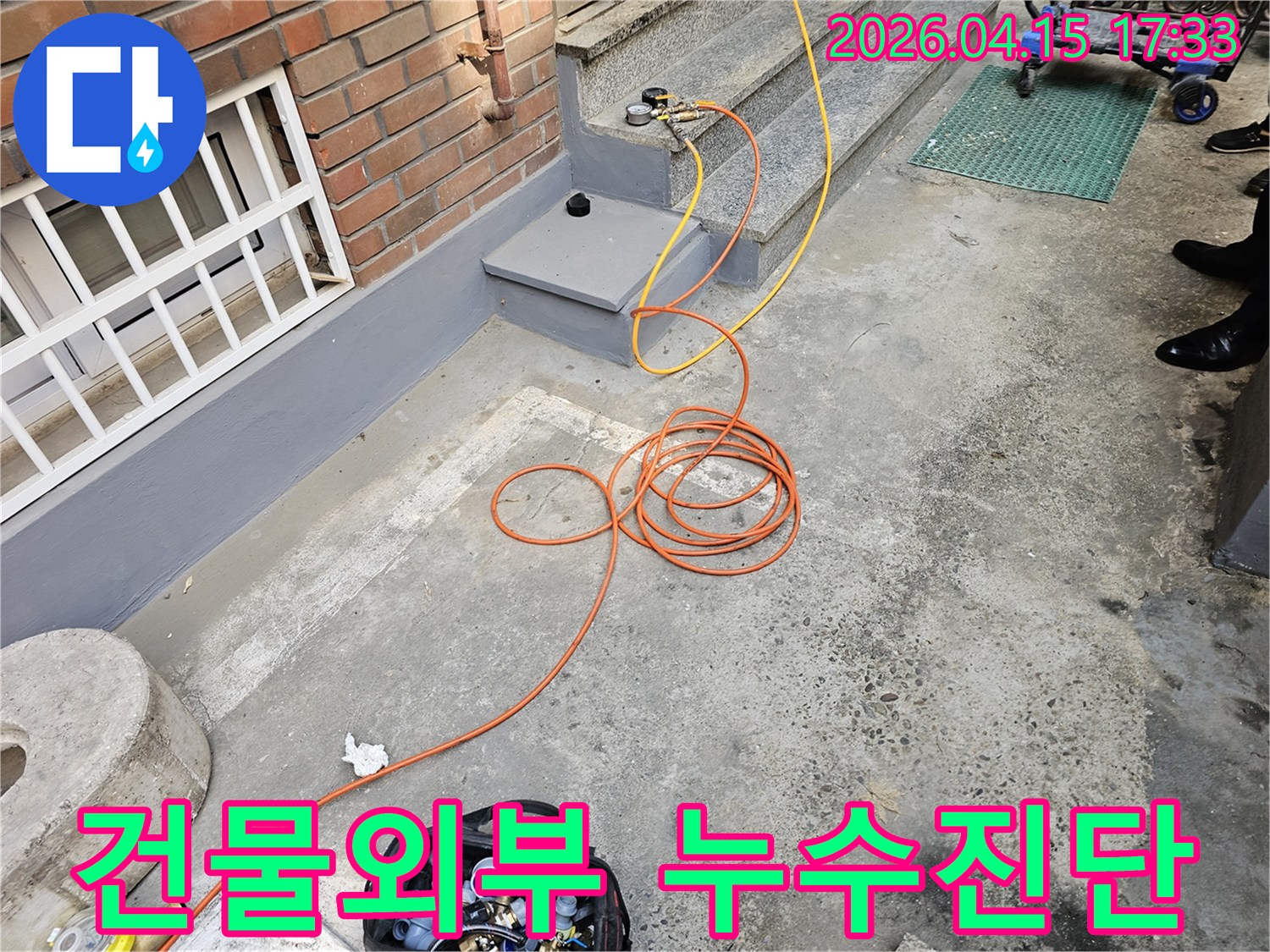 이 이미지는 성동구 건물 외부에서 누수탐지를 위해-전문 장비를 설치하고 압력 검사를 진행하는 현장입니다.