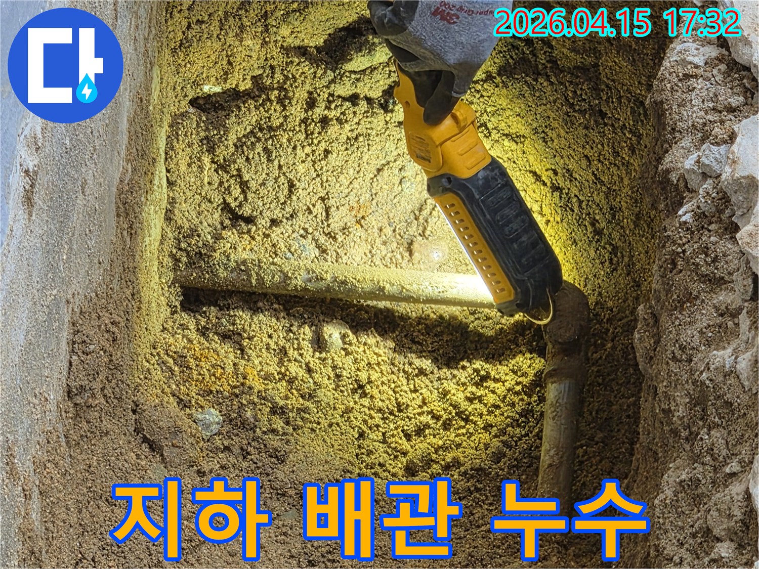 전문가가-손전등을-이용해-땅속에-묻힌-지하-배관의-누수-여부를-꼼꼼히-점검하고-있는-모습입니다.