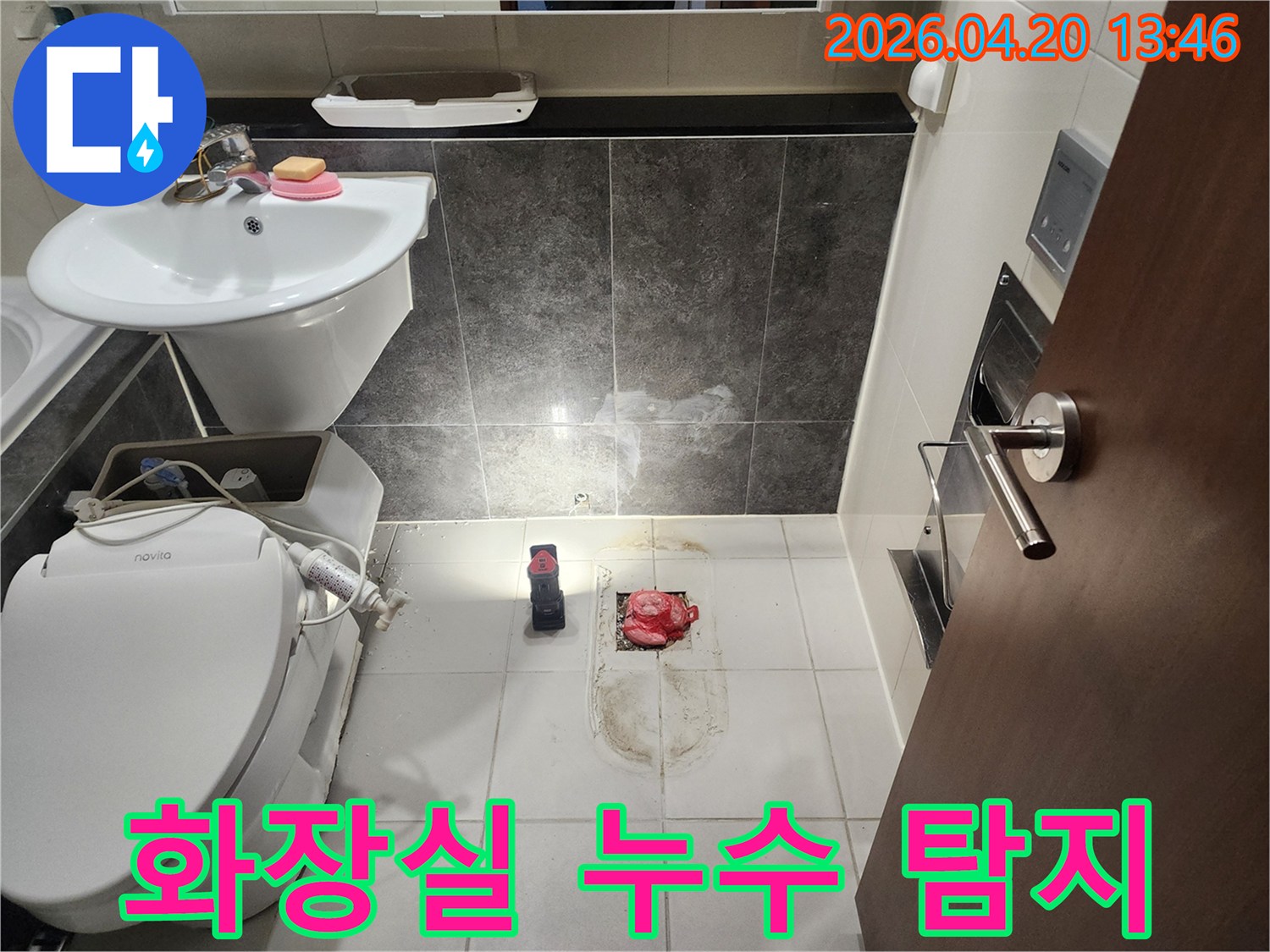 화장실 바닥 배수구 주변의 물기와 벽면 타일의 얼룩을 조명으로 비춰 누수 지점을 꼼꼼하게 탐지하는 모습입니다.