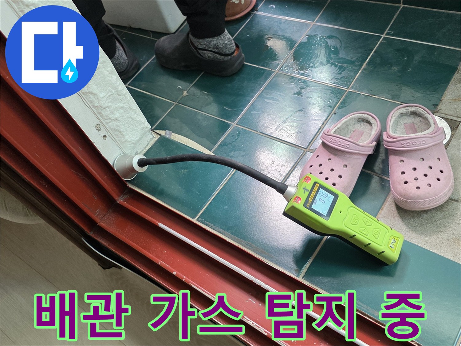 초록색 가스 탐지기를 바닥 근처에 대고 누수 반응을 확인하는 장면