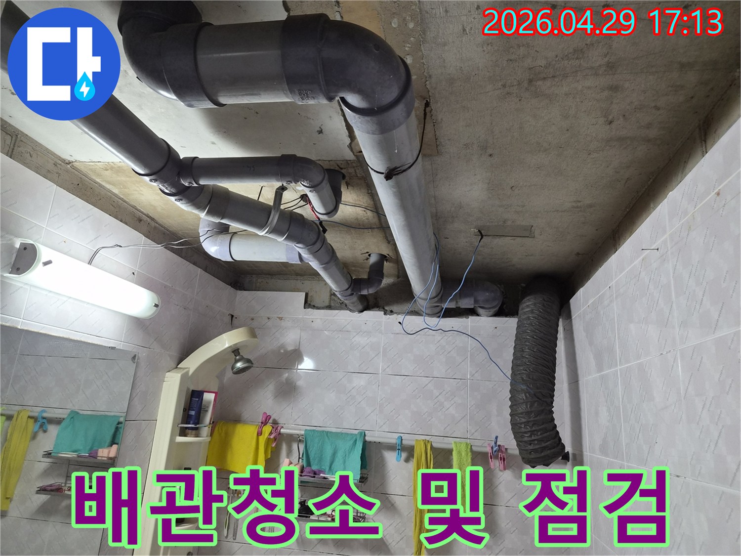 욕실 천장의 노출된 배관들을 청소하며-내부 상태를 점검하고 누수 원인을 찾는 모습입니다