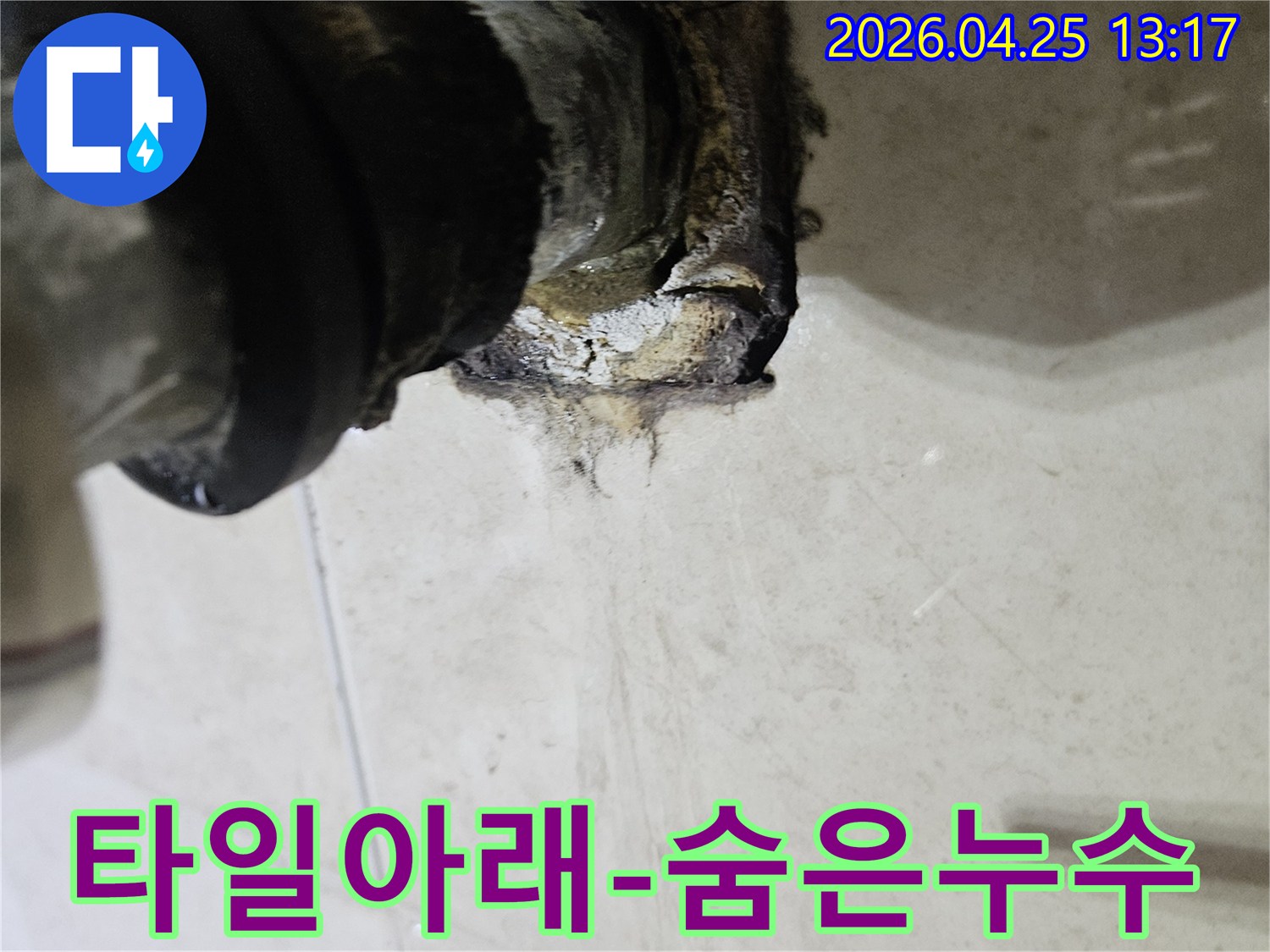 타일 아래 배관 연결 부위에서 발생한 누수로 인해 주변이 오염된 모습을 보여주는 이미지입니다-타일 아래 숨겨진 누수 문제를 해결해야 합니다.