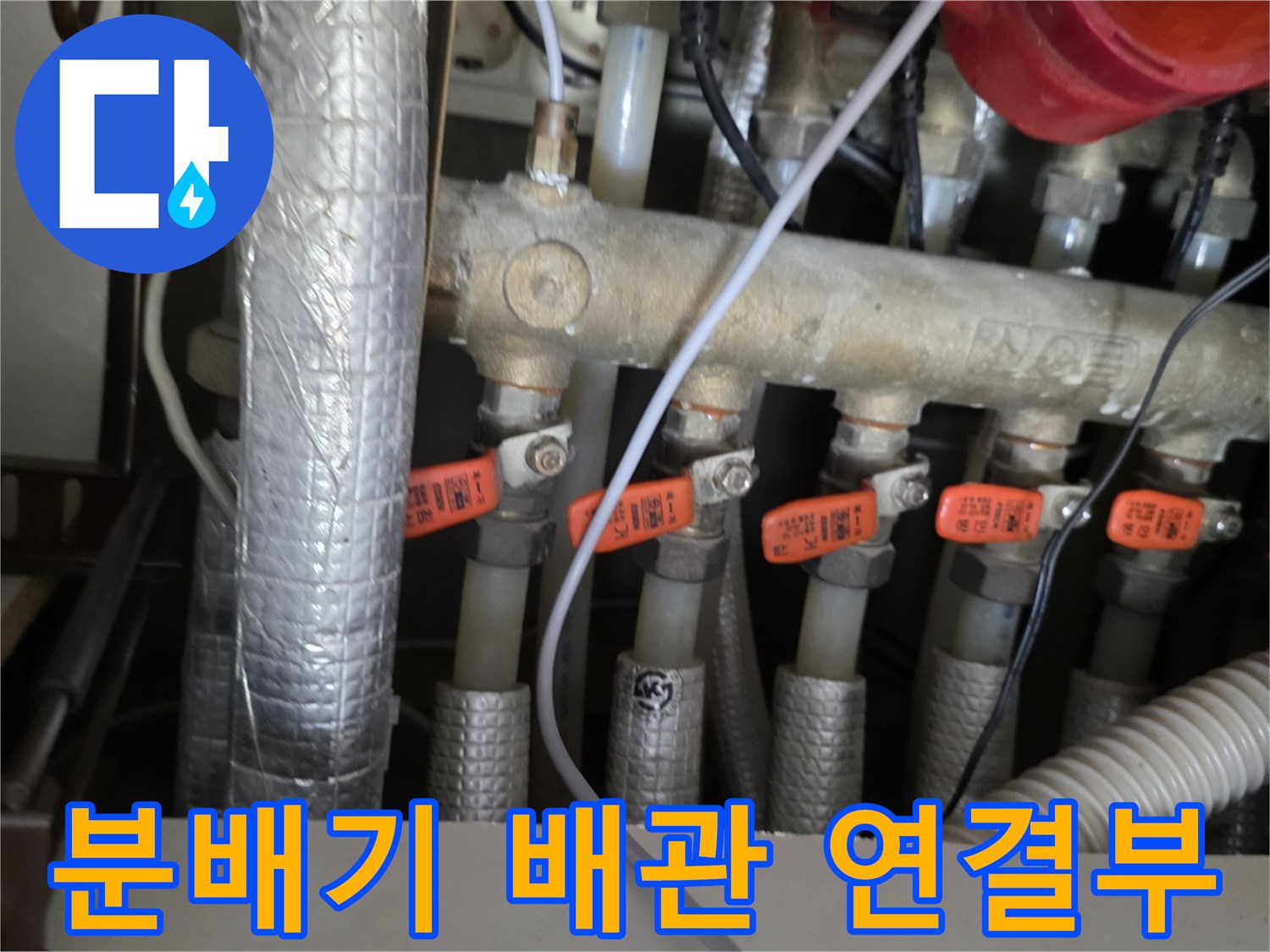 싱크대 아래 난방 분배기 밸브와 은색 보온재로 감싸진 배관들