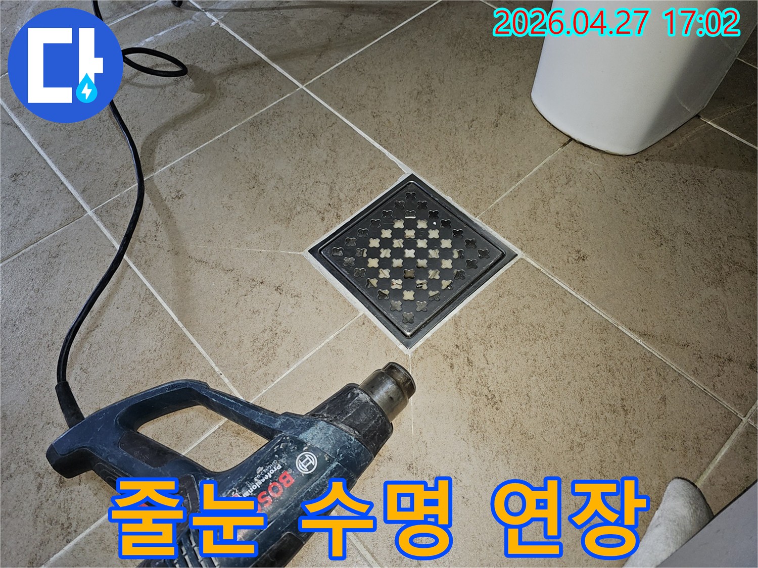 누수 수리 작업 후-엔지니어가-히팅건을 사용하여-타일 줄눈의-습기를 제거하며-수명을 연장하는-모습입니다.