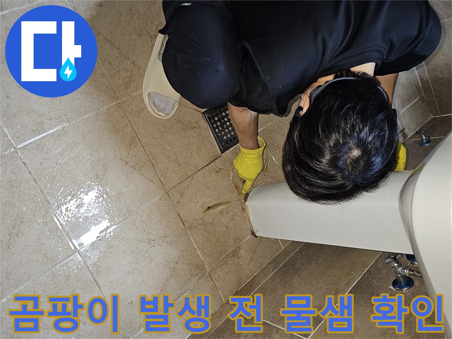 전문 엔지니어가-노란 장갑을 끼고-욕실 바닥의 젖은 타일과-세면대 하단부를-집중적으로 관찰하며-곰팡이 발생 전 물샘을 확인합니다