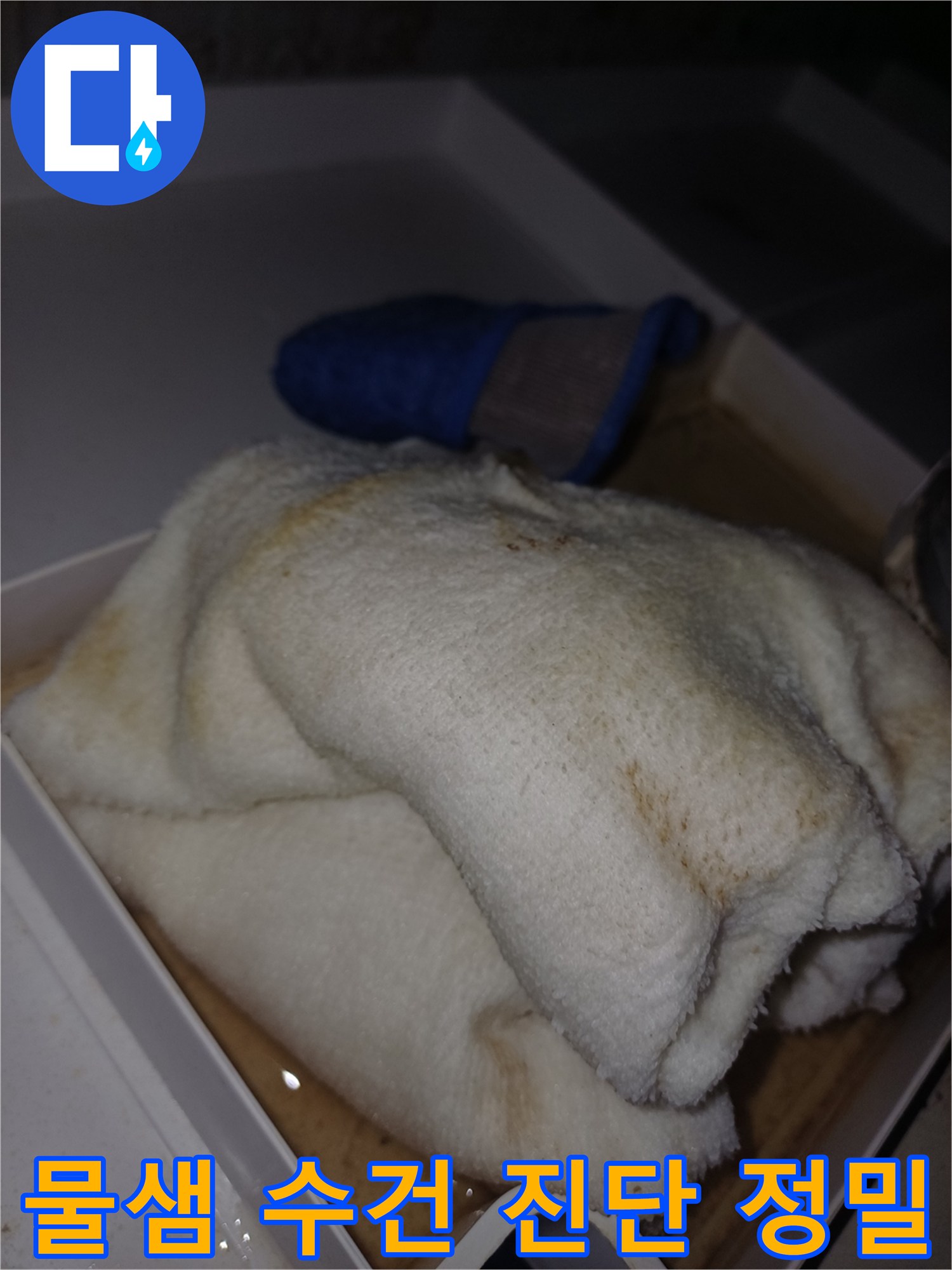 물에 젖어 얼룩이 생긴 수건이 상자 안에 놓여 있는-누수 피해가 진행 중임을 보여주는 현장 사진입니다.