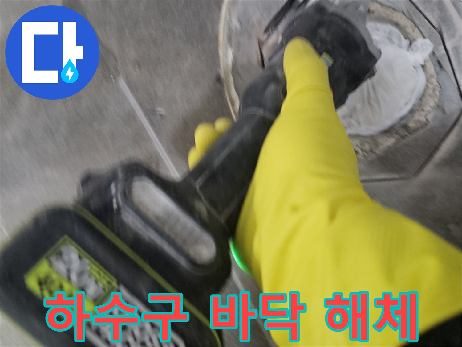 노란색 작업 장갑을 착용한-기술자가-전동 공구로-하수구 주변의 바닥을-조심스럽게 해체하는 모습입니다.