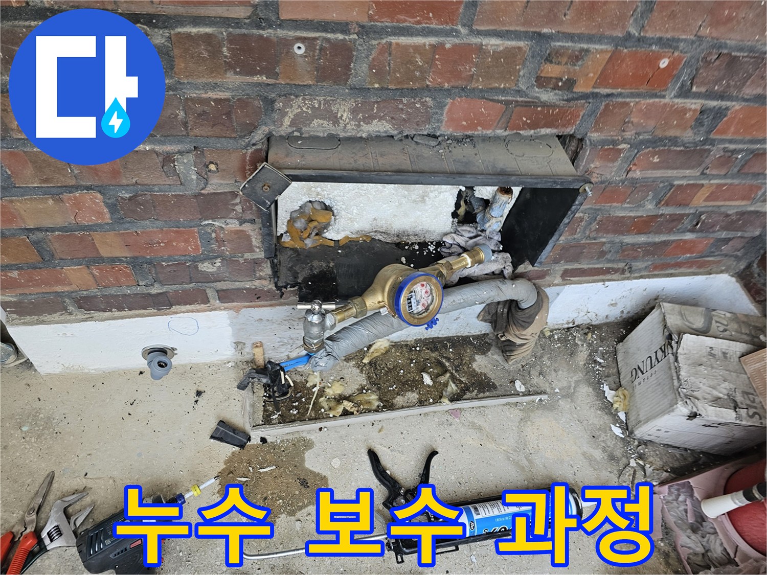 누수 공사 중 수도 계량기와 연결된 배관을 점검하고 보수하는 작업 현장입니다