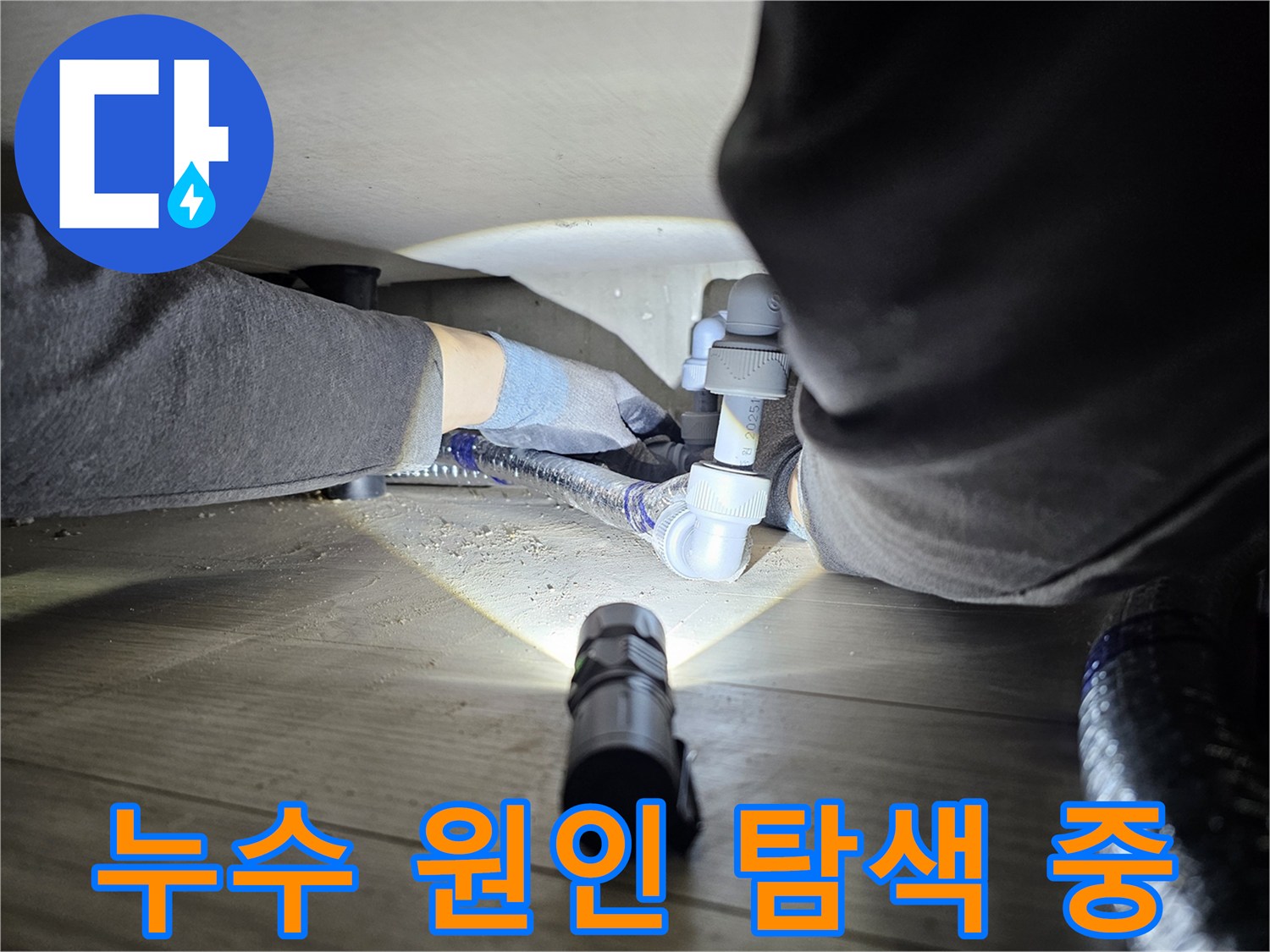 누수-전문가가-손전등을-이용해-어두운-배관-하부를-정밀하게-조사하는-장면