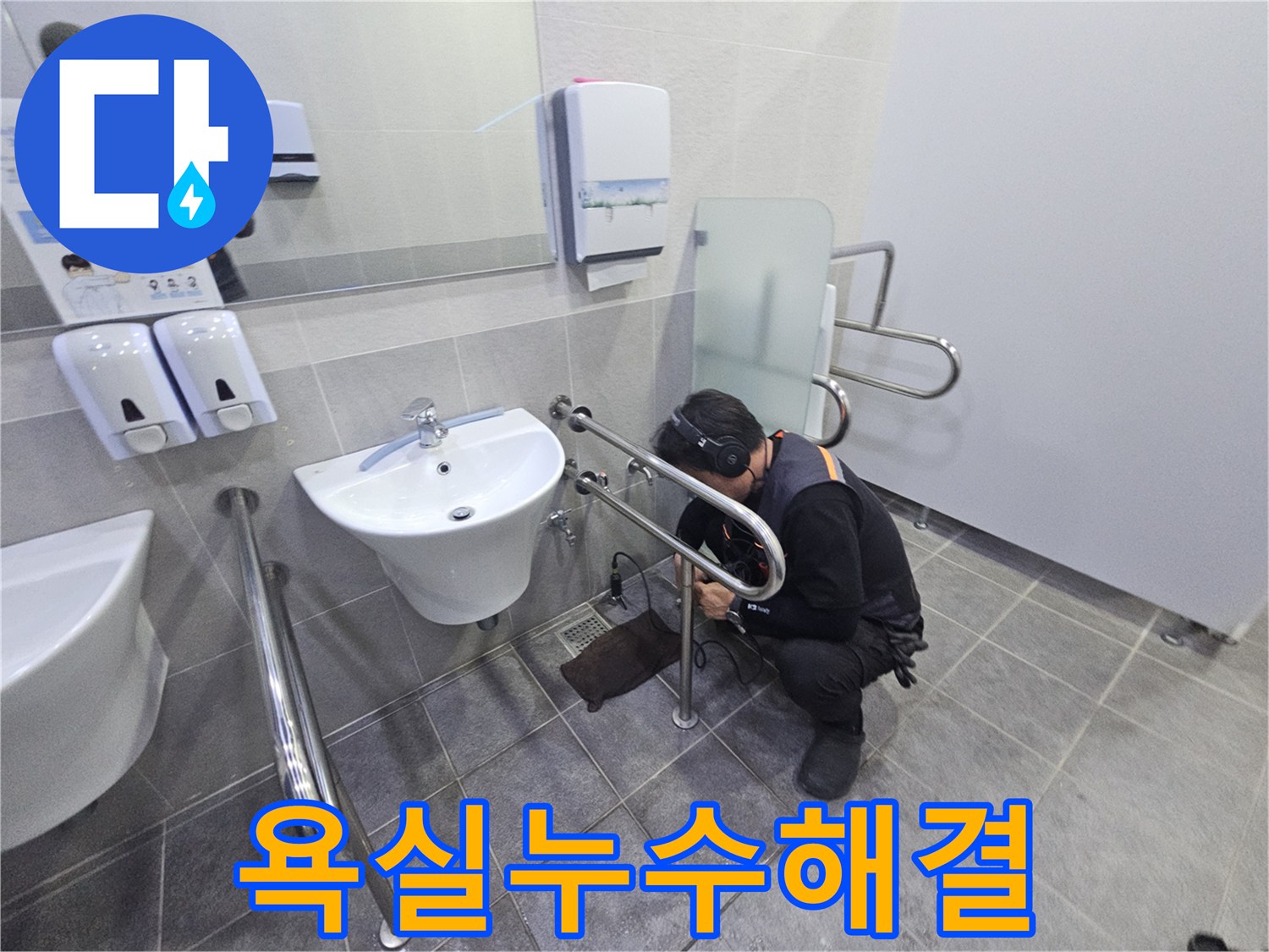헤드폰을 착용한 기술자가-공용 화장실의 세면대 배관에서-미세한 누수 지점을 찾아내고 있습니다.