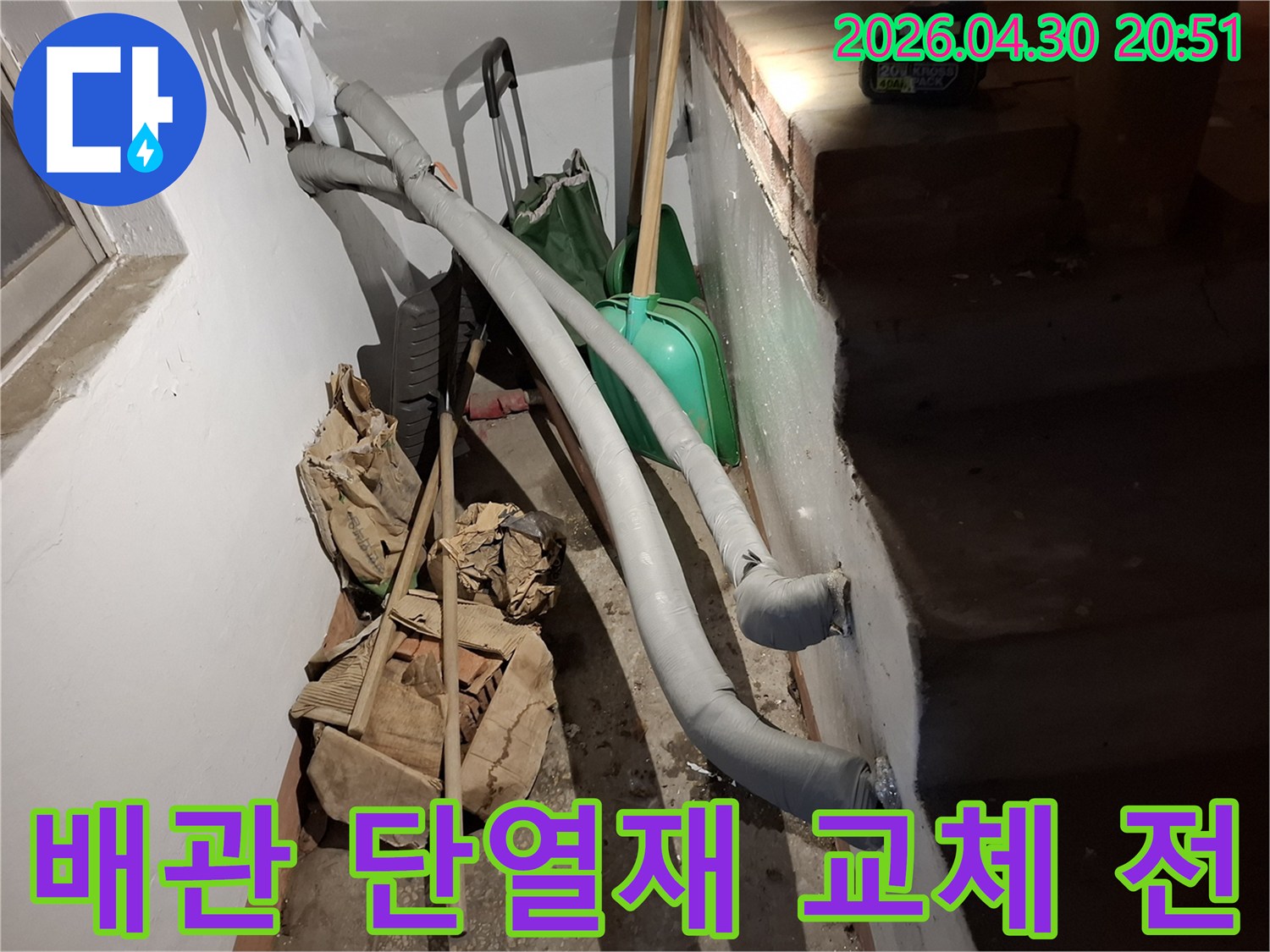 이 이미지는 지하 공간에 설치된 단열 처리된 배관과-주변에 놓인 공사 자재들을 보여줍니다.