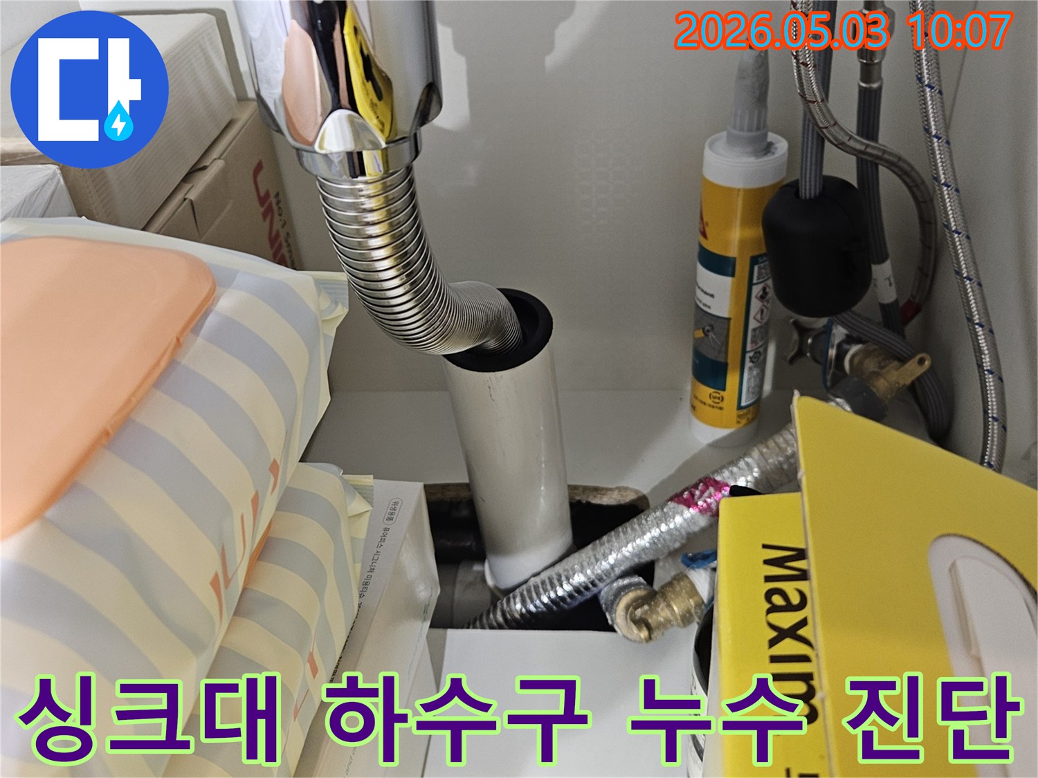 싱크대 하부의 배수관 연결 부위와-유연한 호스 주변을 집중적으로 점검하여 누수 원인을 찾는 모습