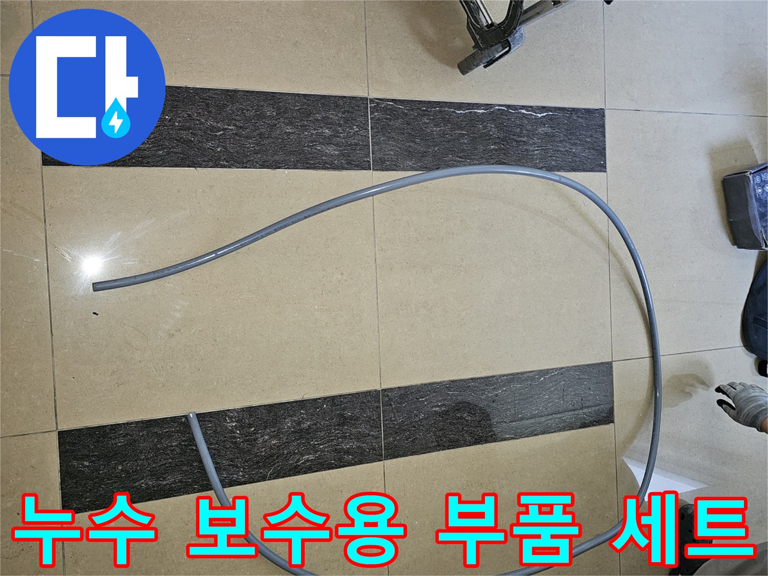 바닥 타일 위 회색 배관과 전문 장비 케이스 모습