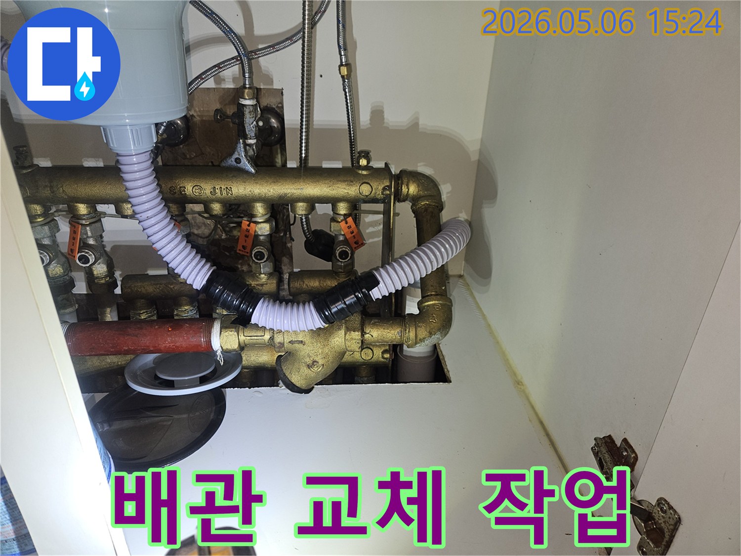 이 이미지는 주방 하부장-내부의 노후되거나-손상된 배관을-새로운 배관으로 교체하는-전문적인 작업 과정을-보여주고 있습니다.