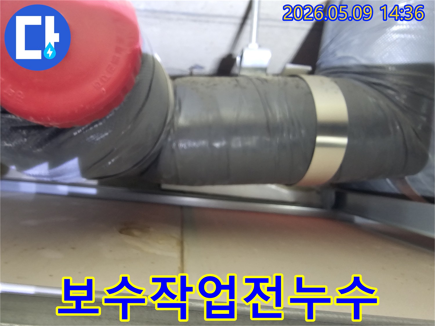 회색-배관-아래-물기가-고여있는-모습을-담은-보수-작업-전-현장-사진입니다