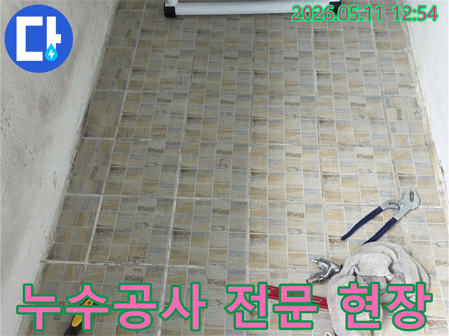 누수 공사 현장에서-타일 벽면과-전문 작업에 필요한 공구들이 놓여있는 모습