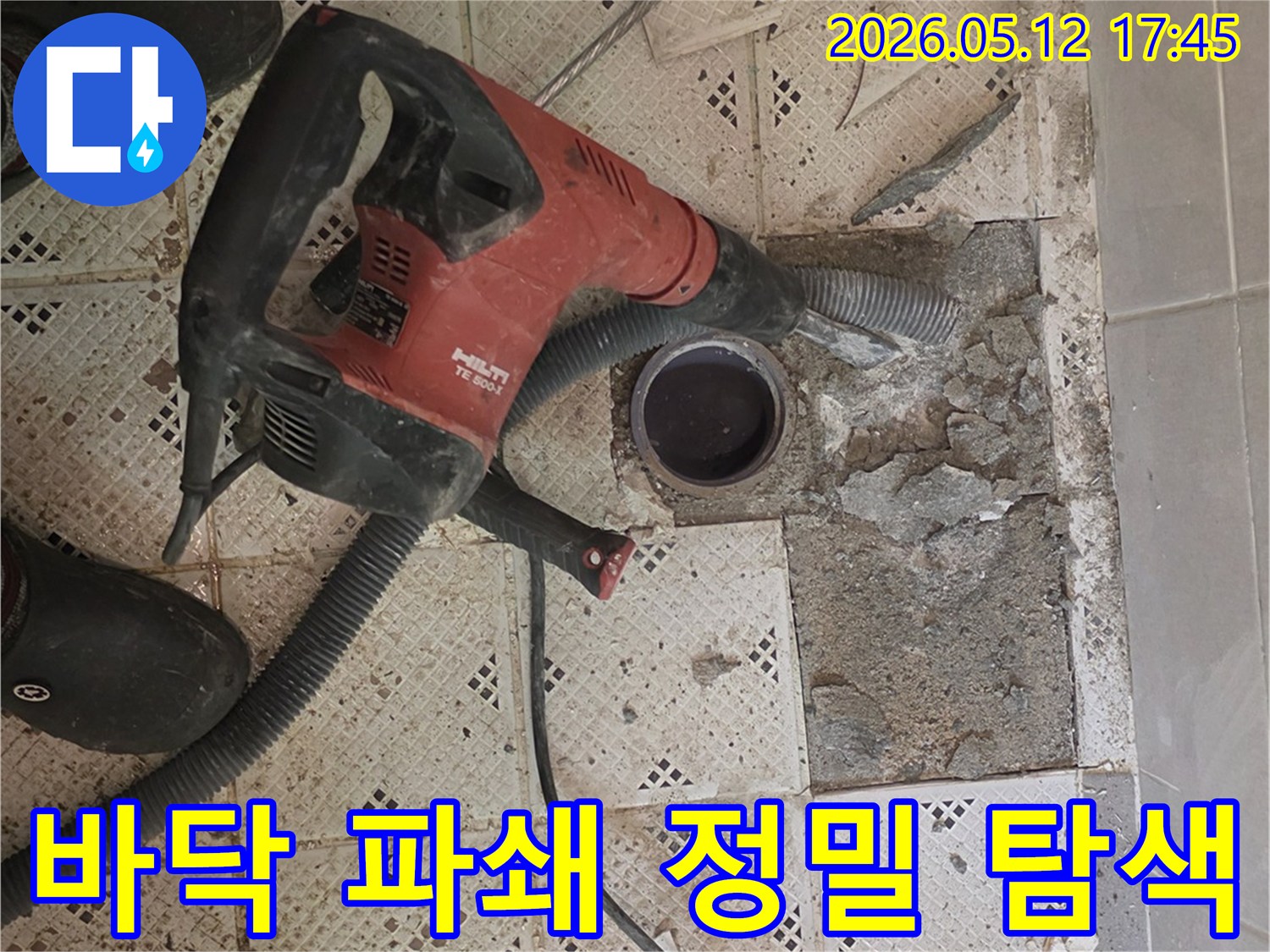 누수 지점을 정밀 탐색하기 위해-바닥 타일을 파쇄하는-전문 장비와-작업자의 발이 보이는-작업 현장입니다.