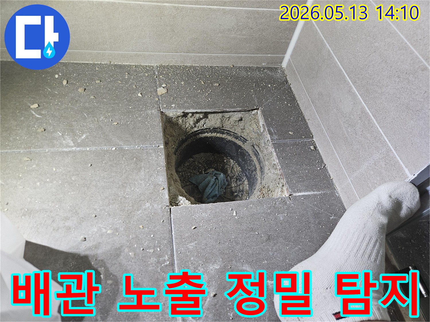 누수 지점을 정확히 찾기 위해 바닥 타일을 제거하고 배관을 드러낸 모습입니다-전문가가 누수 흔적을 면밀히 살피고 있습니다